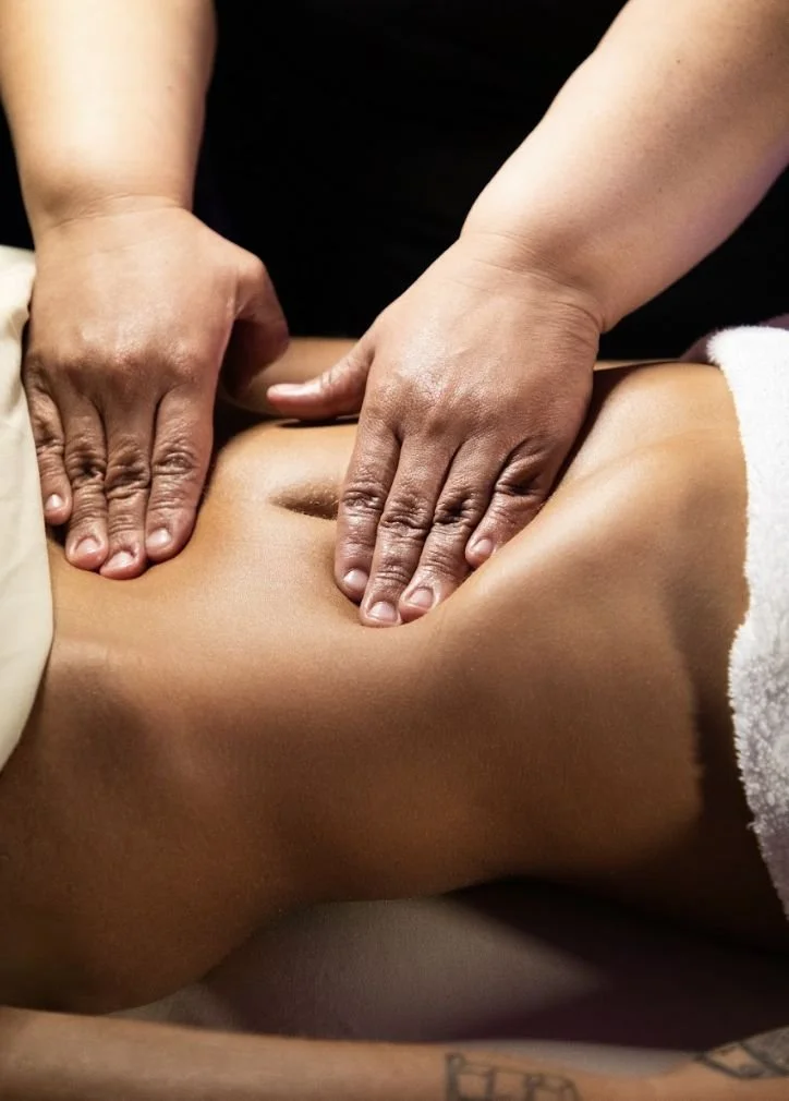 Close-up of a person receiving a massage on their lower back from a massage therapist.
