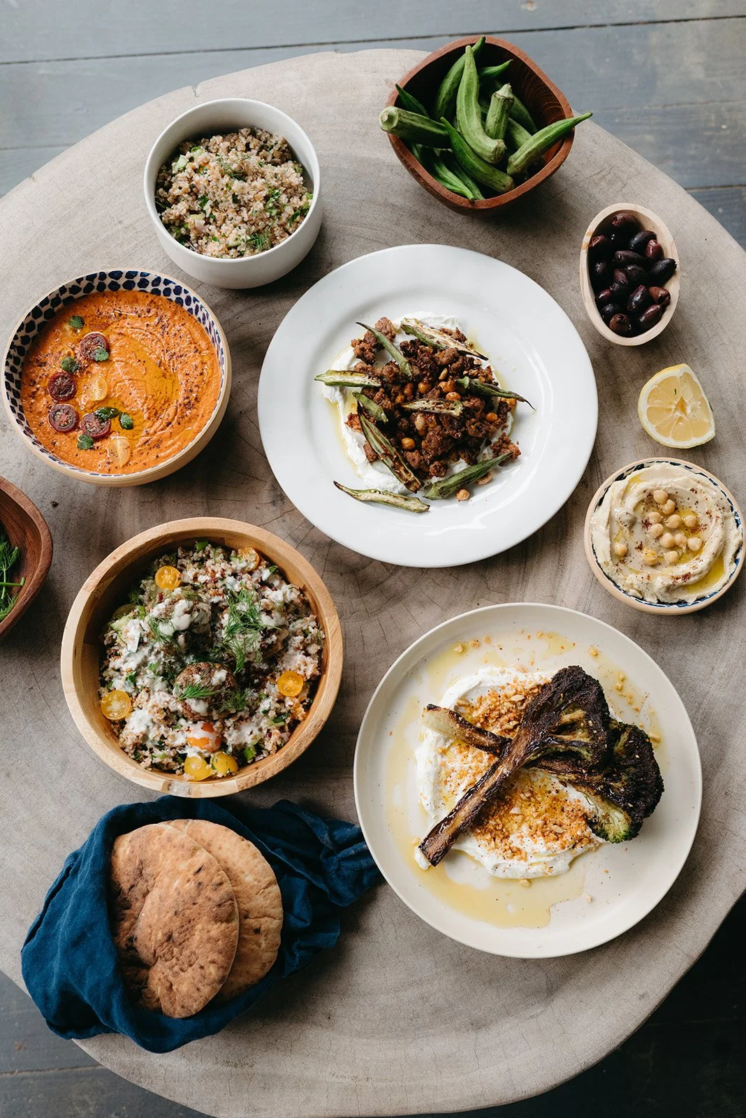 Assorted Middle Eastern dishes on a round table, including grilled vegetables, grains, dips, and flatbread.