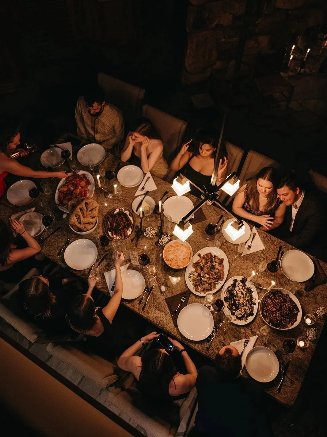 People sitting around a dinner table with food and drinks, celebrating at night.