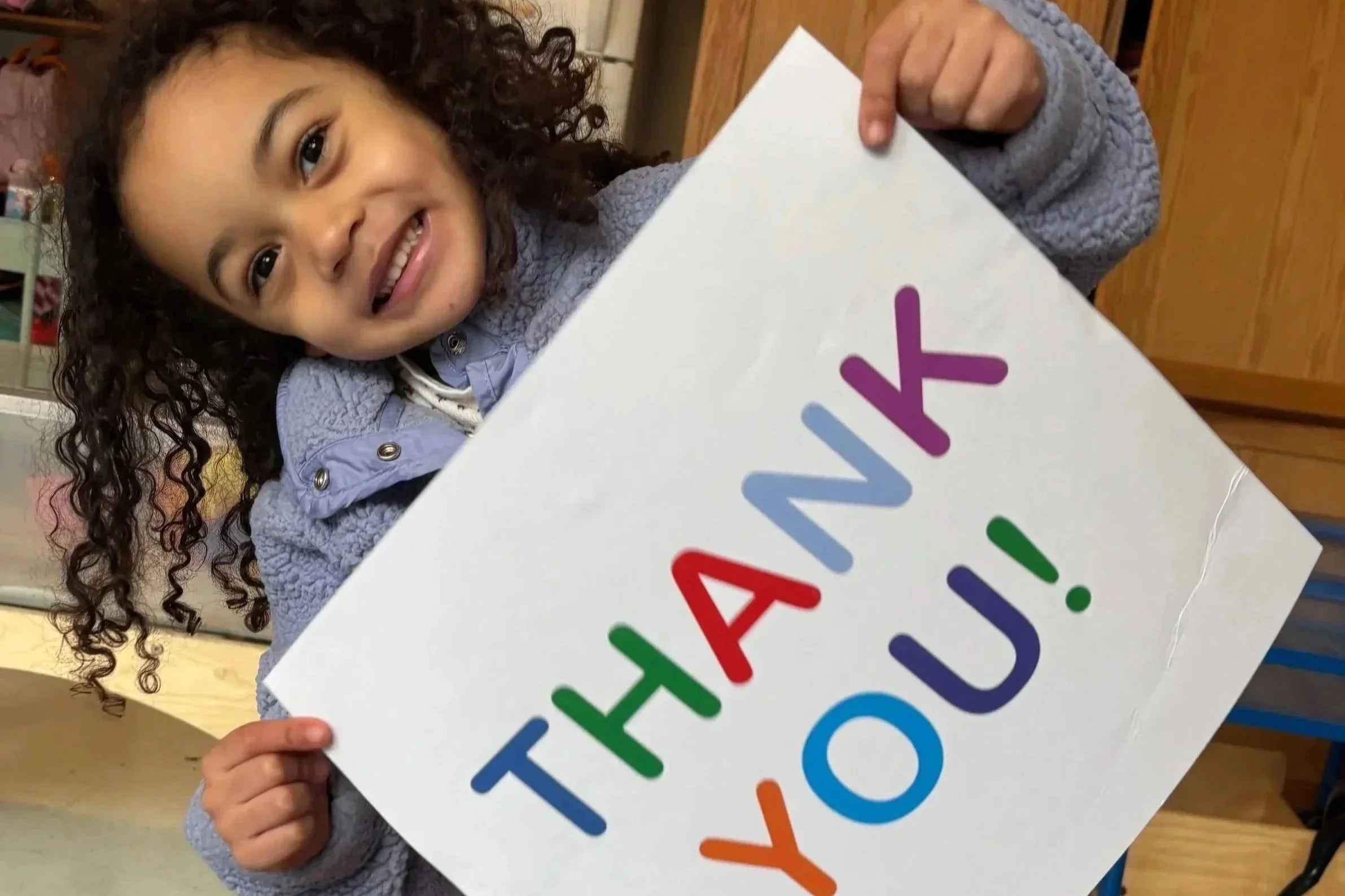 A child holds up a paper sign that says thank you