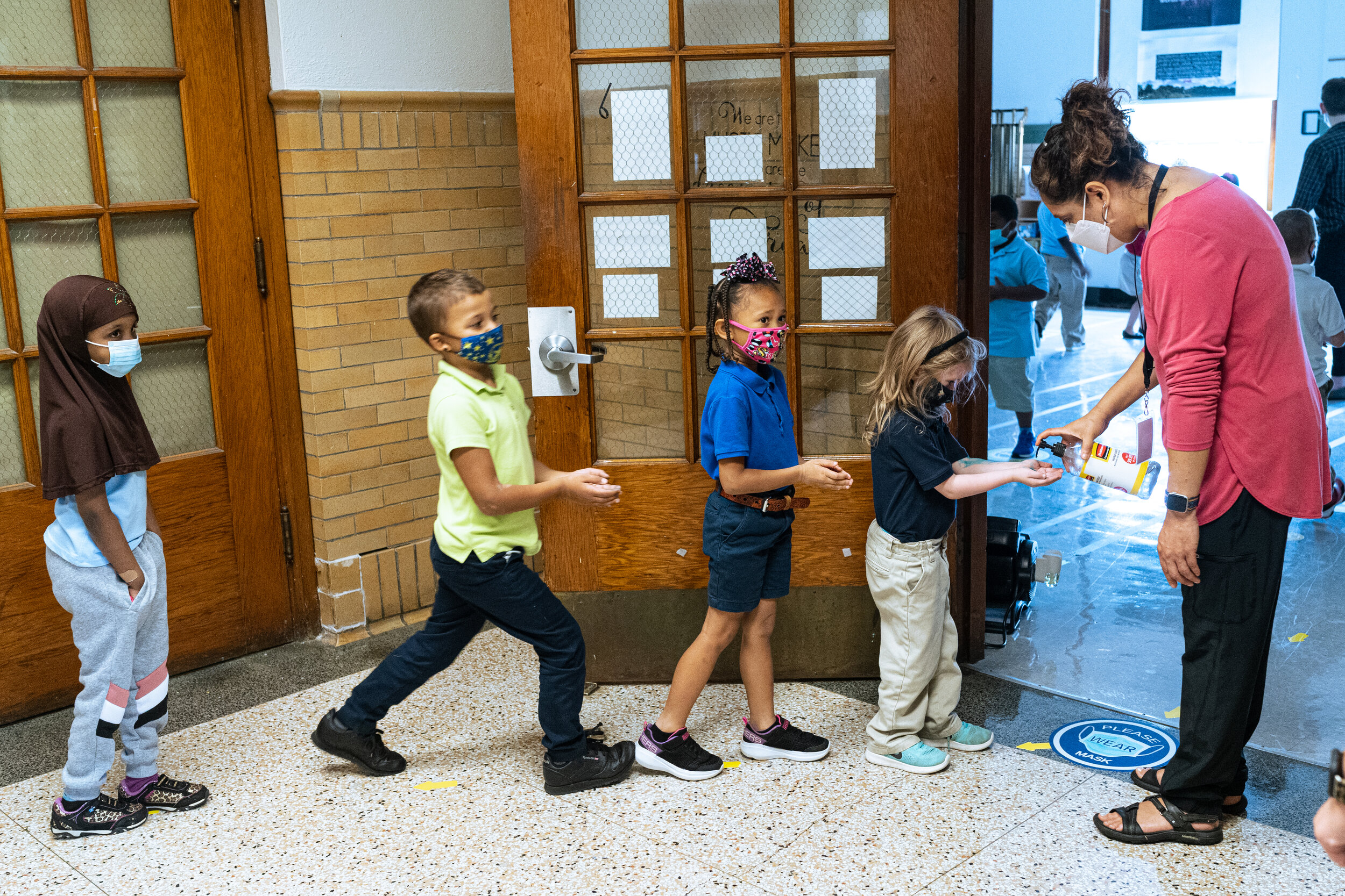 Quesada greets her second grade music class and gives them each a squirt of hand sanitizer as they enter her classroom.
