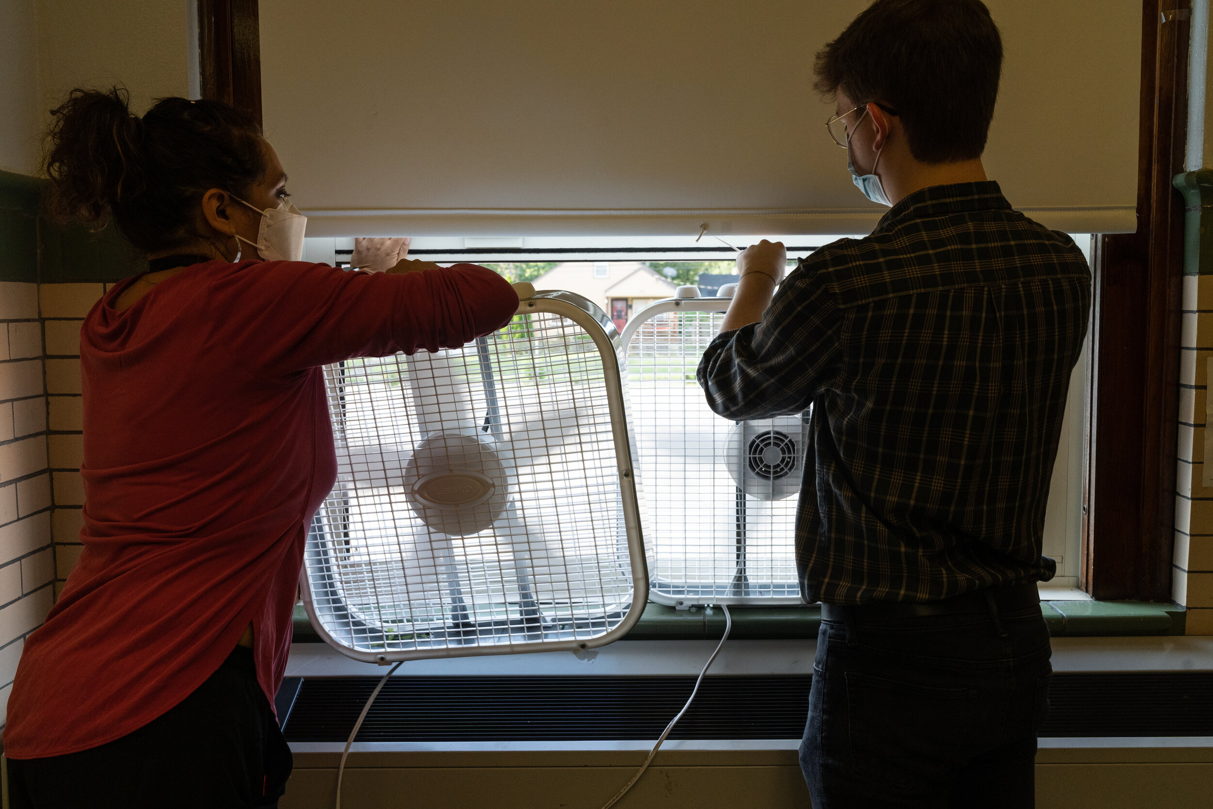 Quesada and student teacher Christopher Wolfzorn place box fans in open windows to keep air circulating. After doing her own research, Quesada decided to face one fan outward and one fan inward for better circulation.