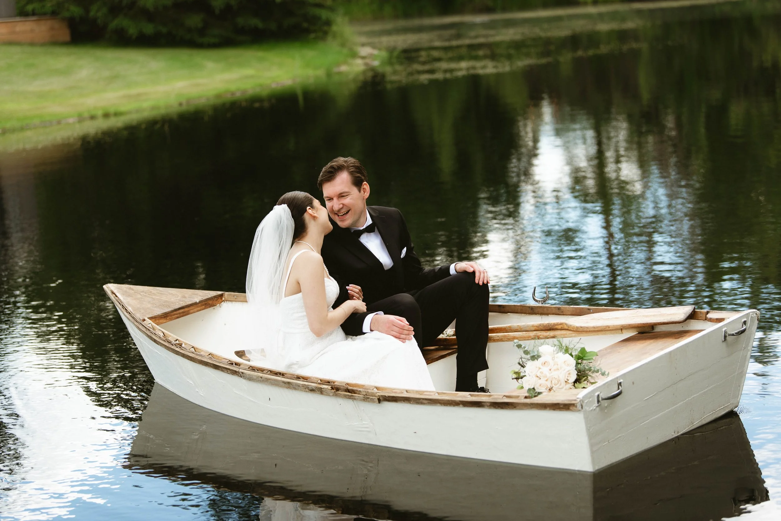 Bride and groom laughing together in a boat during their outdoor wedding portraits