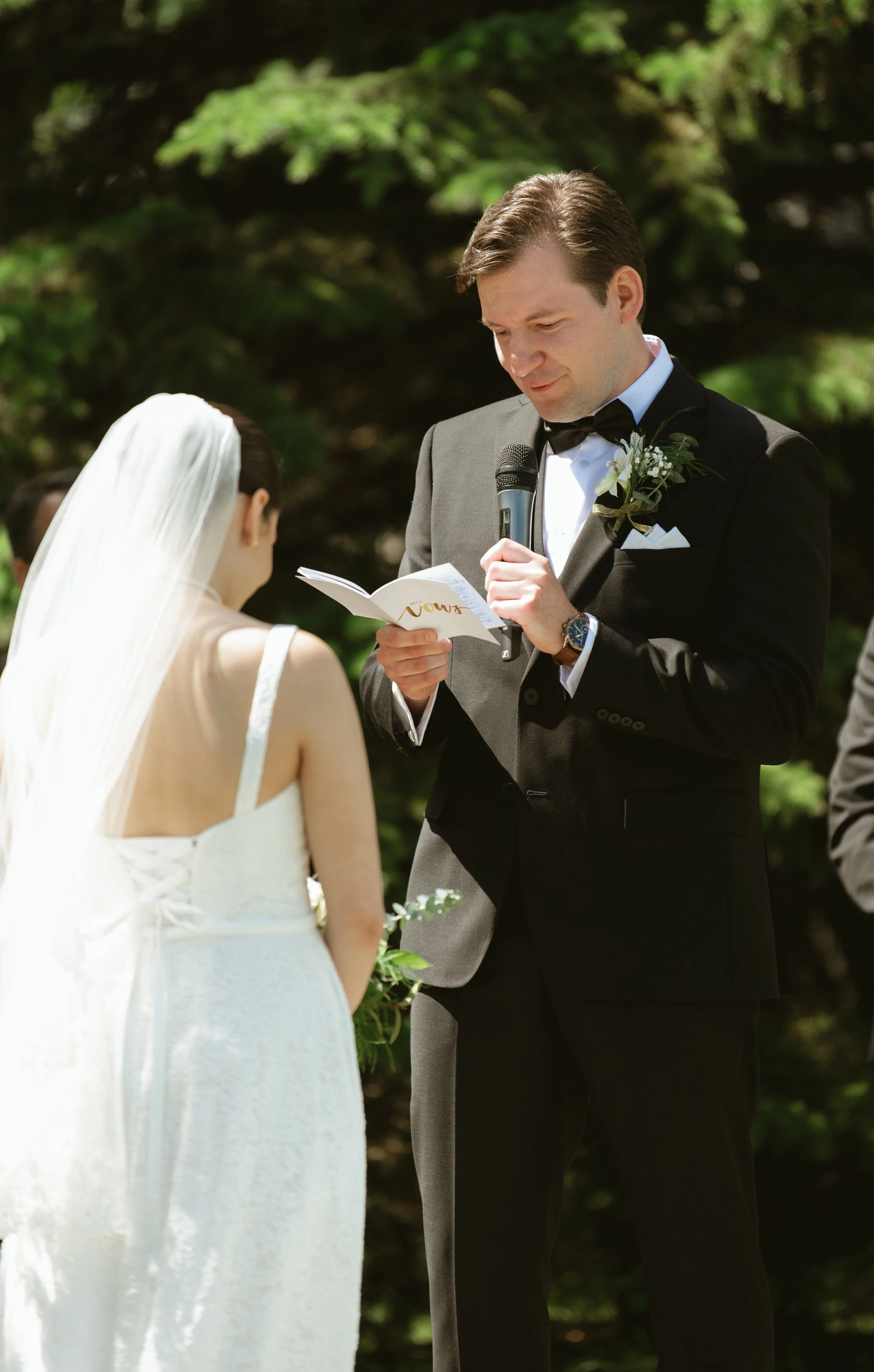Groom ready his wedding vows to the bride during their outdoor ceremony at Pine & Pond Wedding Venue in Ponoka County, Alberta, photographed by Danielle Aichelle Photography