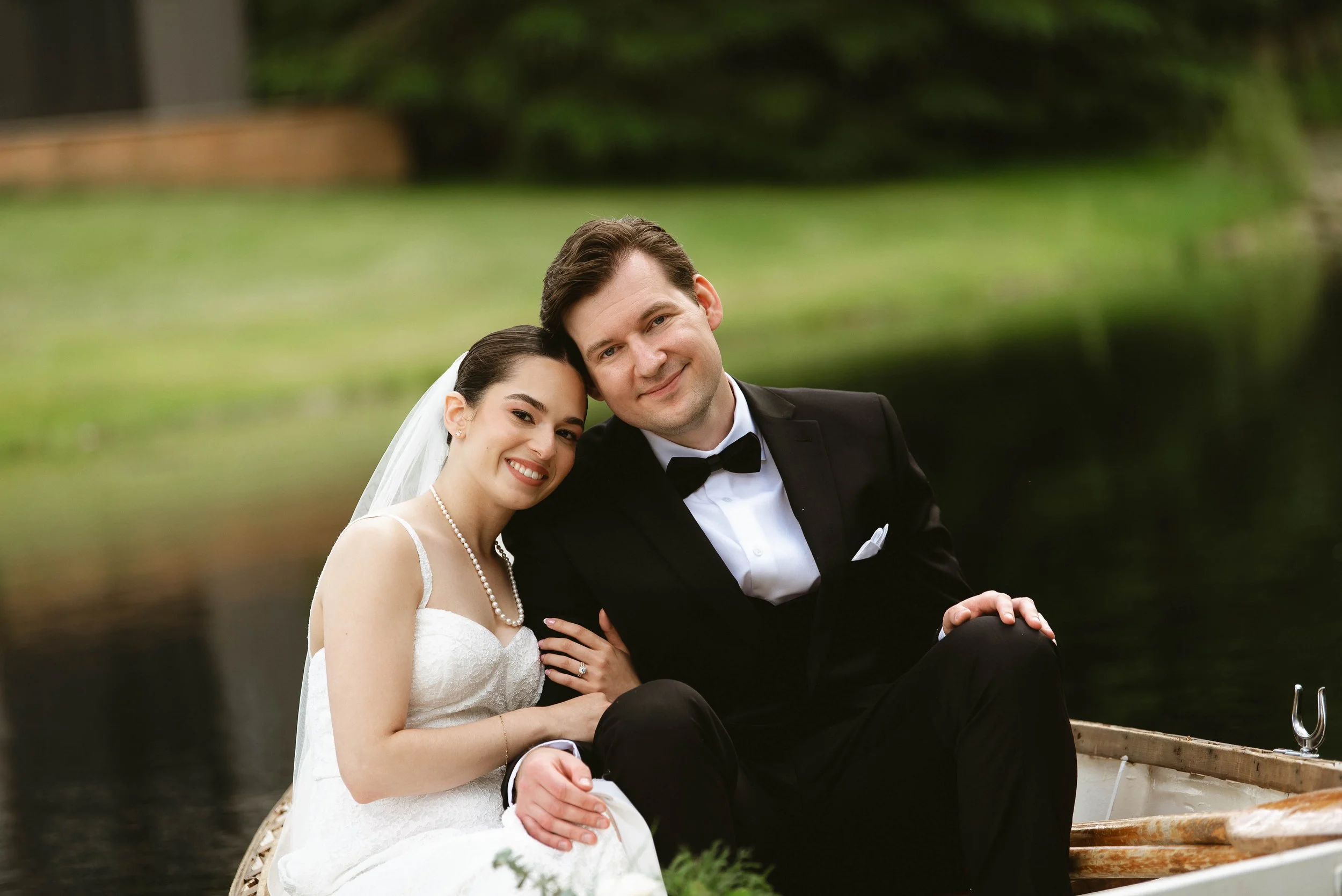 Bride and groom sitting closely together smiling during their outdoor wedding portraits