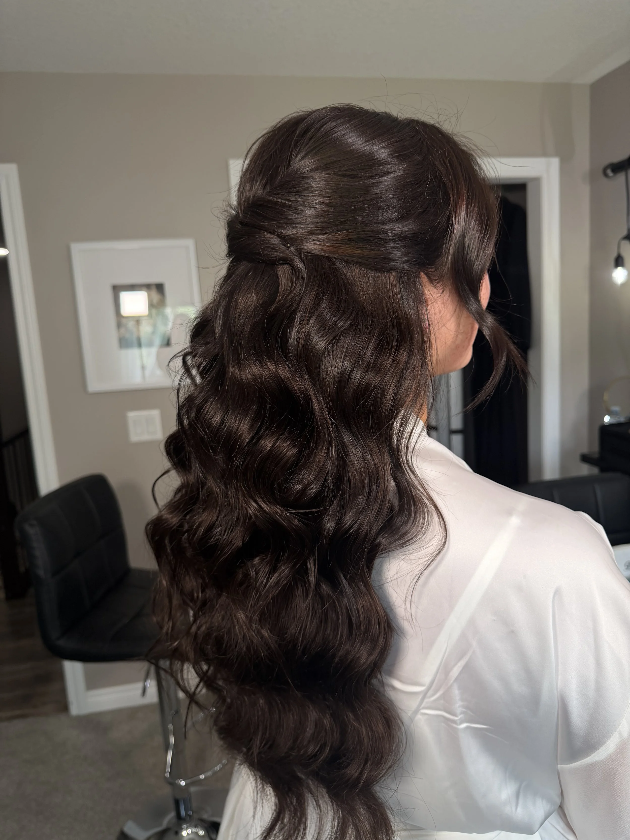 Back view of a romantic half up bridal hairstyle with soft waves, styled by Red Deer bridal hairstylist Danielle Aichelle Artistry at 52 north wedding venue