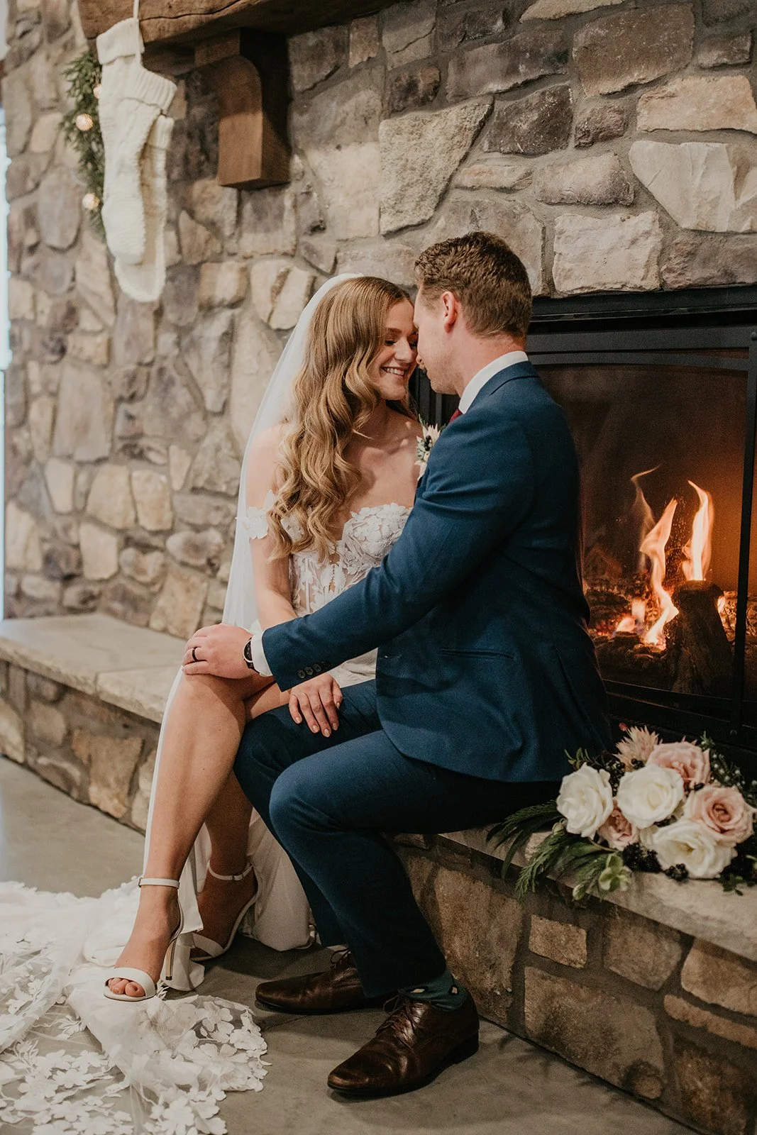 Bride and groom beside a fireplace at a cozy winter wedding in Central Alberta