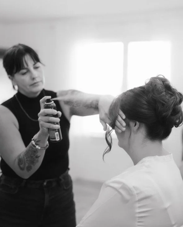 Bridal hairstylist styling bride's hair on her wedding morning.