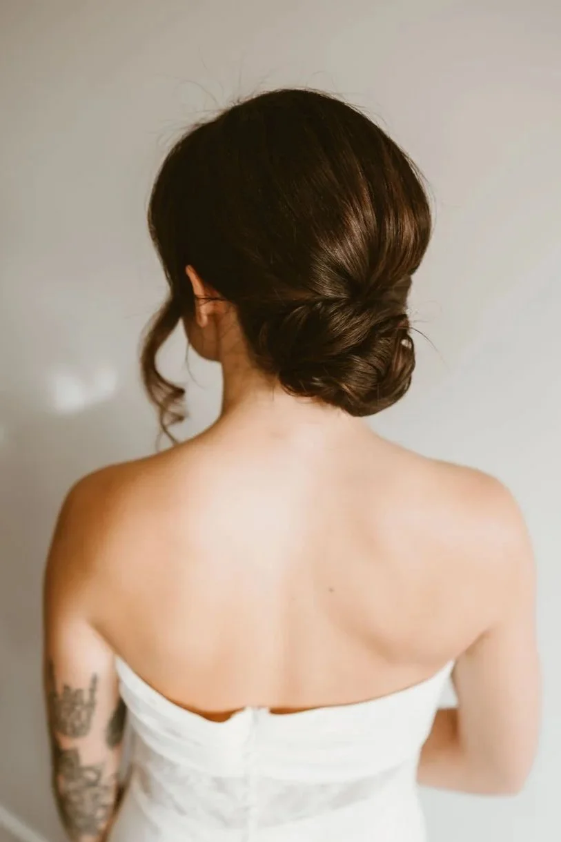 Back view of a bride with dark hair styled in an elegant low bridal updo.
