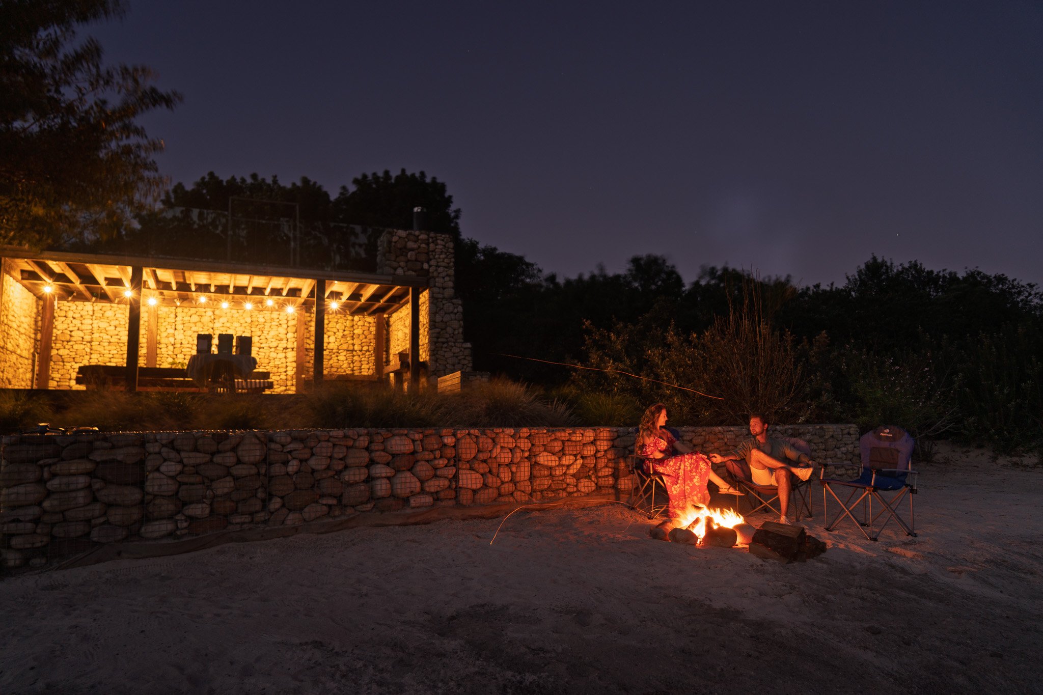 Outdoor campfire experience at Ludus Magnus, with guests gathered around a fire beneath the Franschhoek night sky.
