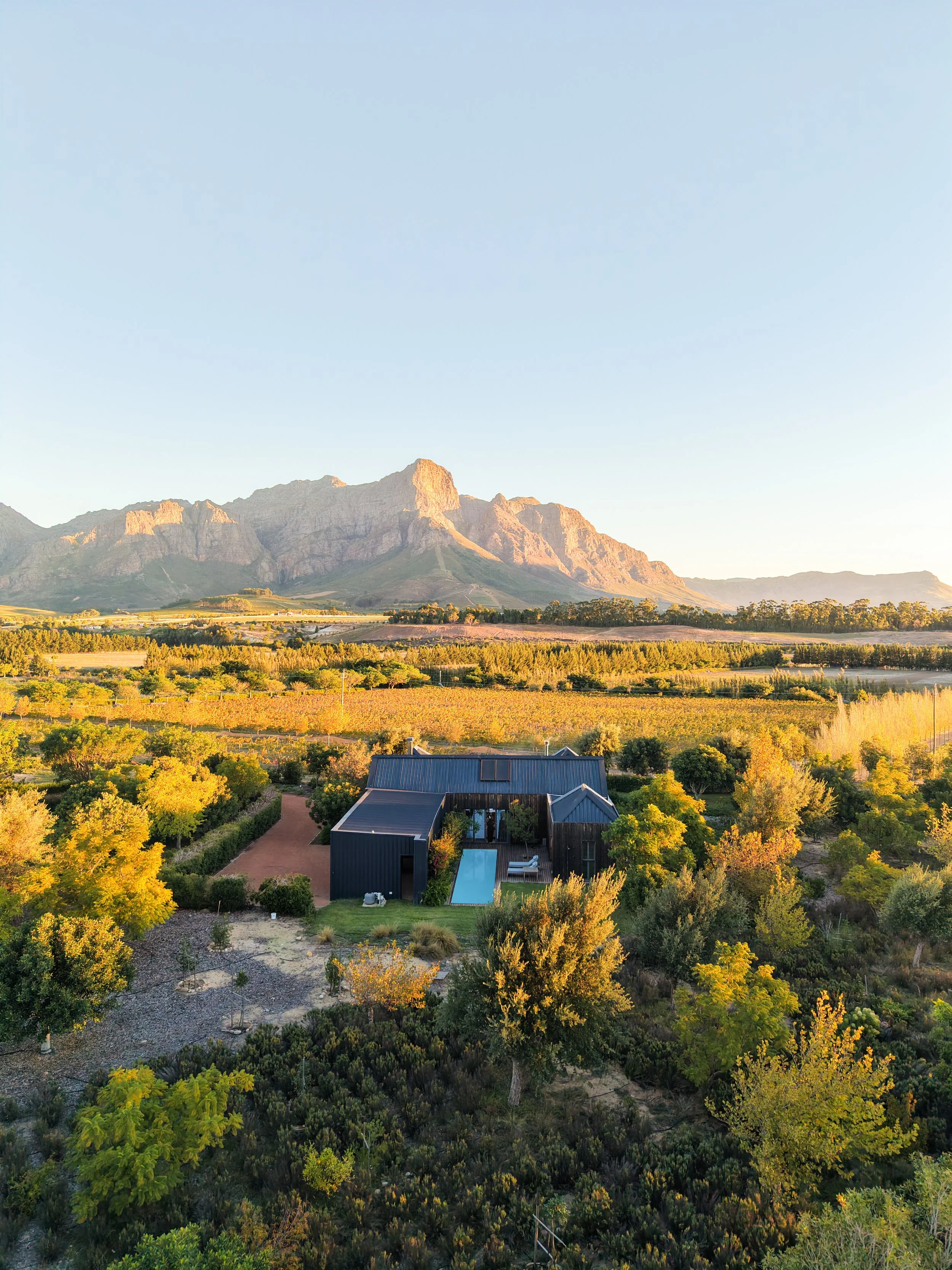 Aerial view of a private luxury villa at Ludus Magnus, featuring a swimming pool, lush gardens and panoramic views of the Franschhoek mountains.
