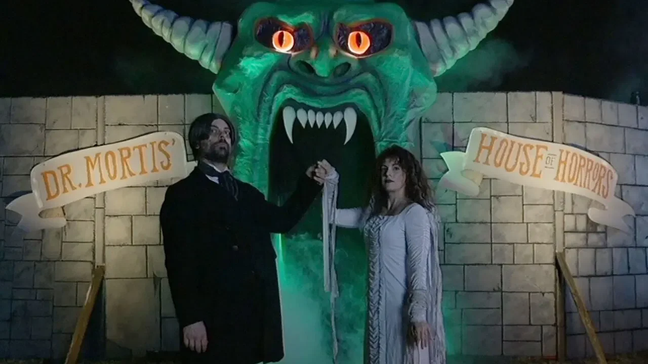 Two people in front of a house of horrors in V/H/S Halloween (2025)