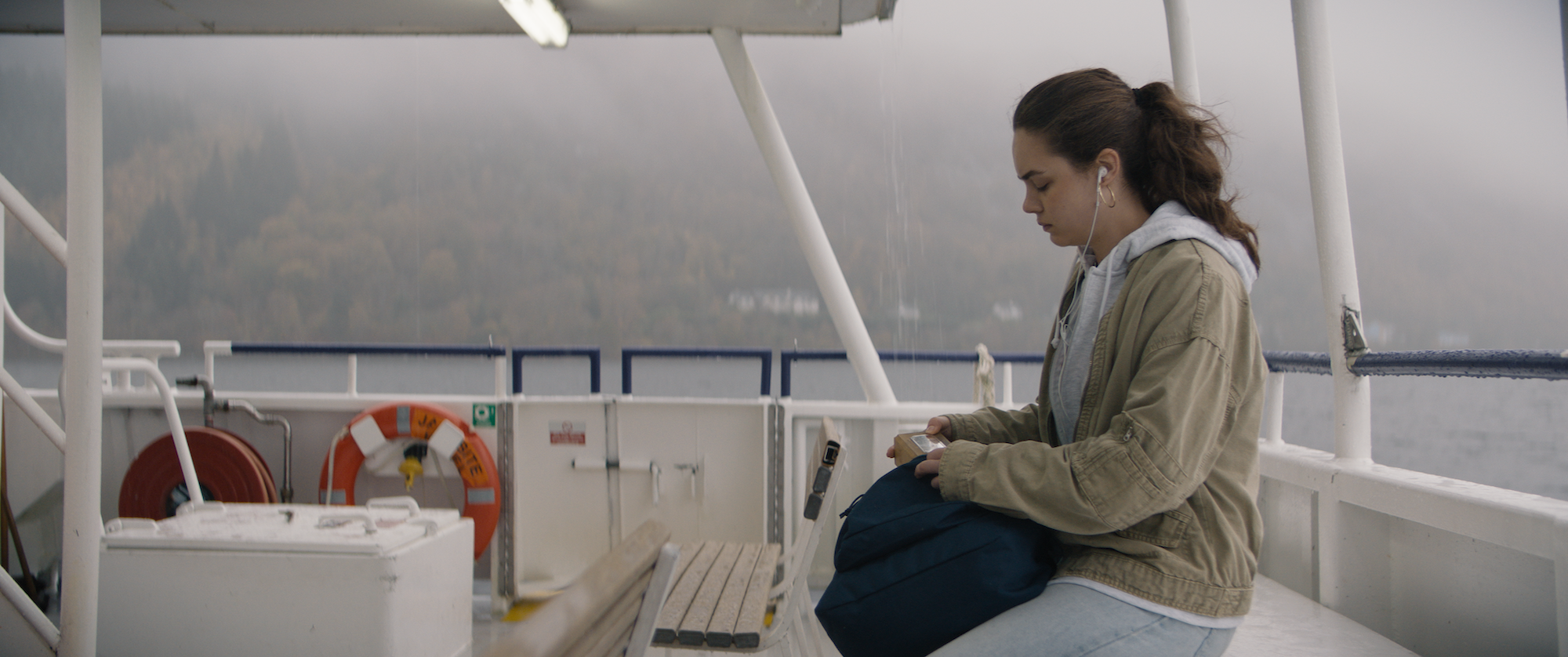 Red Riding (2026) girl on boat with earphones in