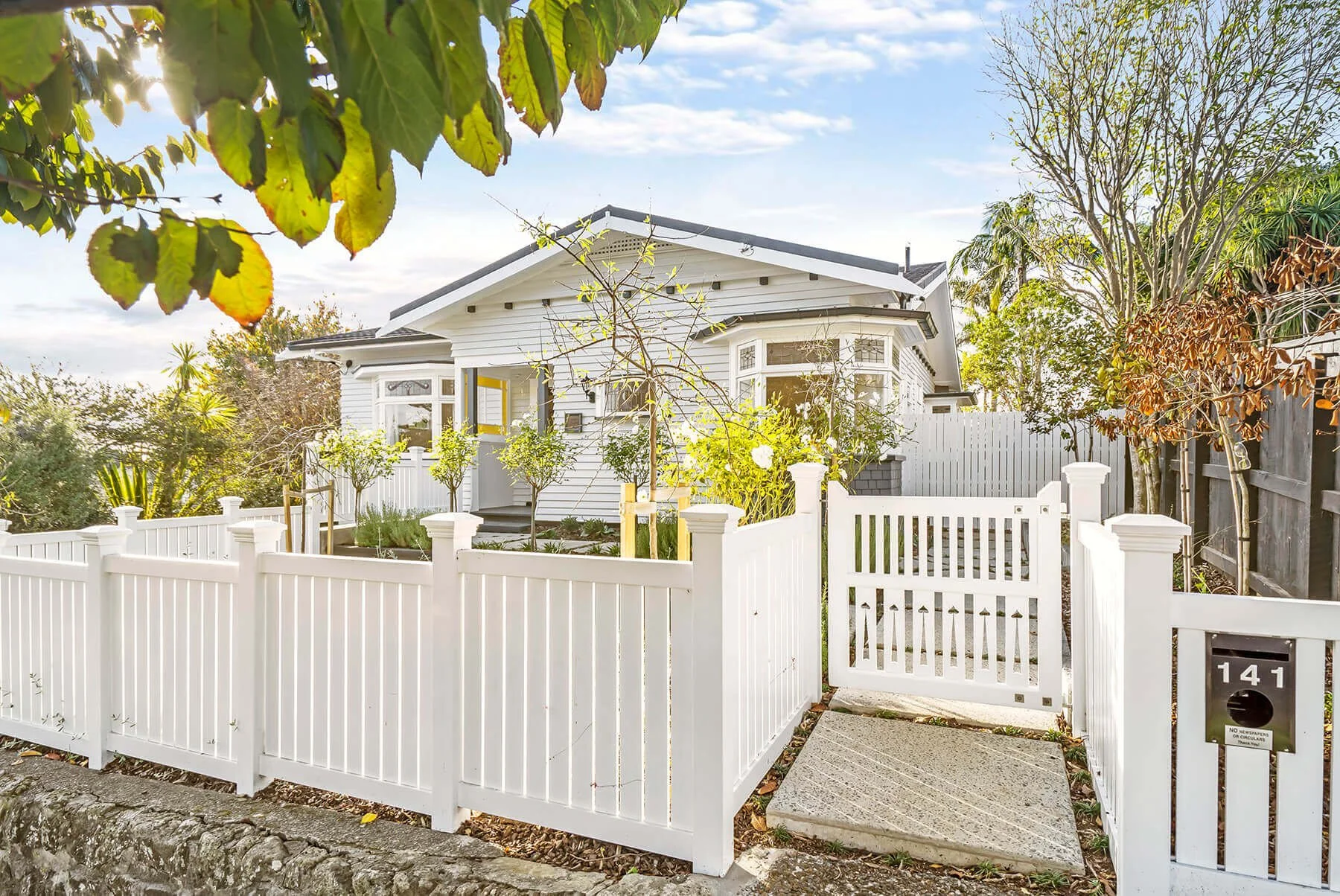 Character villa renovation in Auckland with white picket fence and landscaped entry, restored by Sync Renovations.
