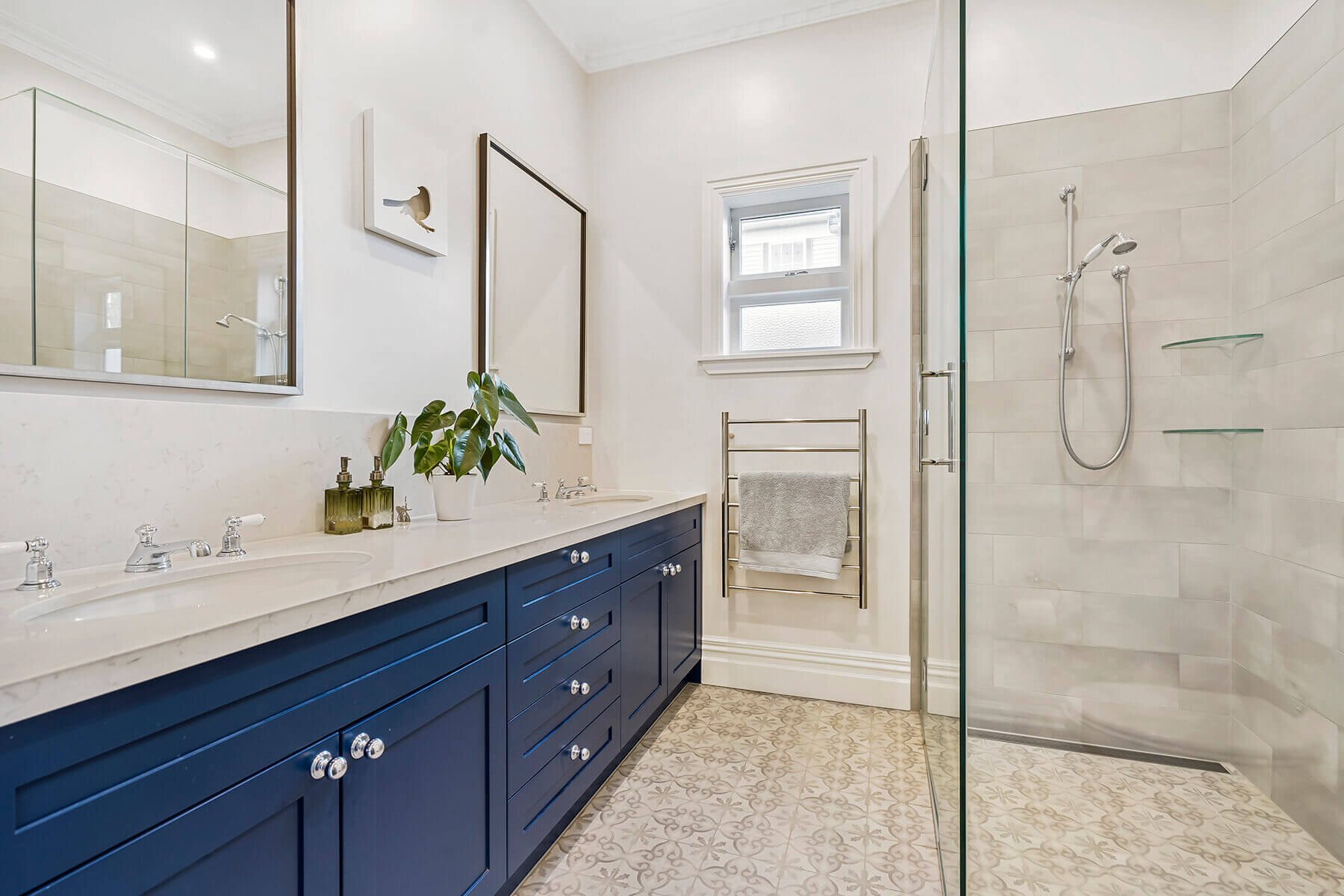 Elegant bathroom renovation with navy vanity, marble-look benchtop, and glass shower in Auckland by Sync Renovations.
