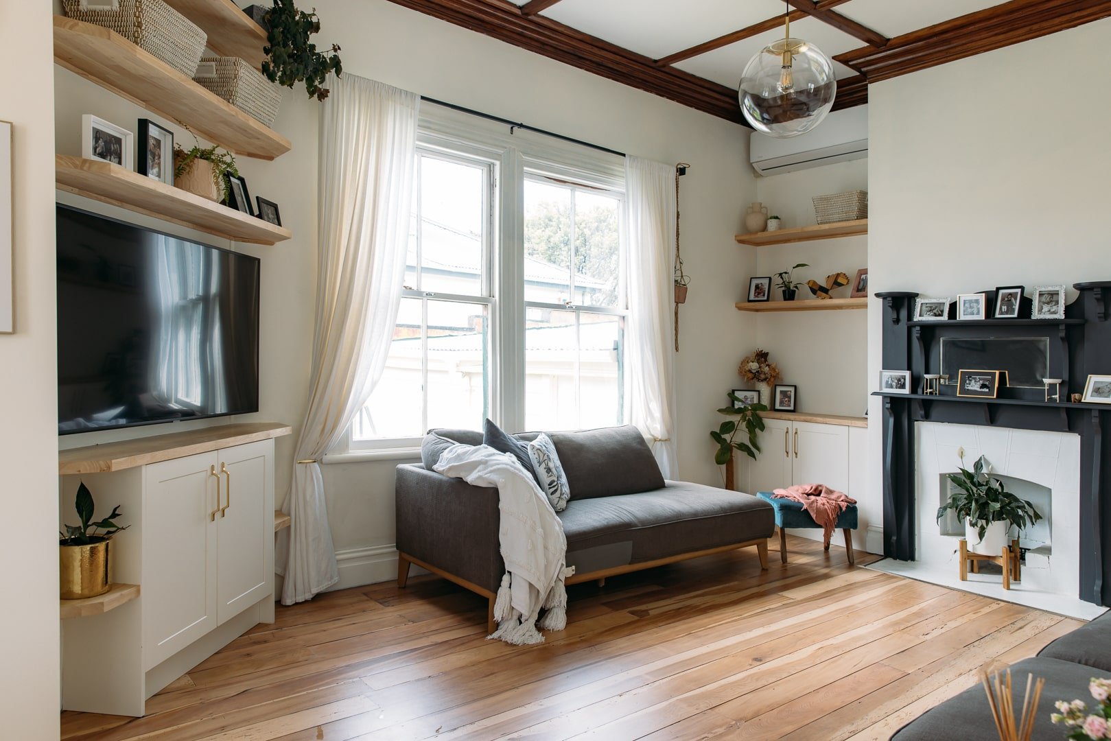 Lounge renovation in Auckland with white cabinetry, timber flooring, natural light, and custom shelving by Sync Renovations.
