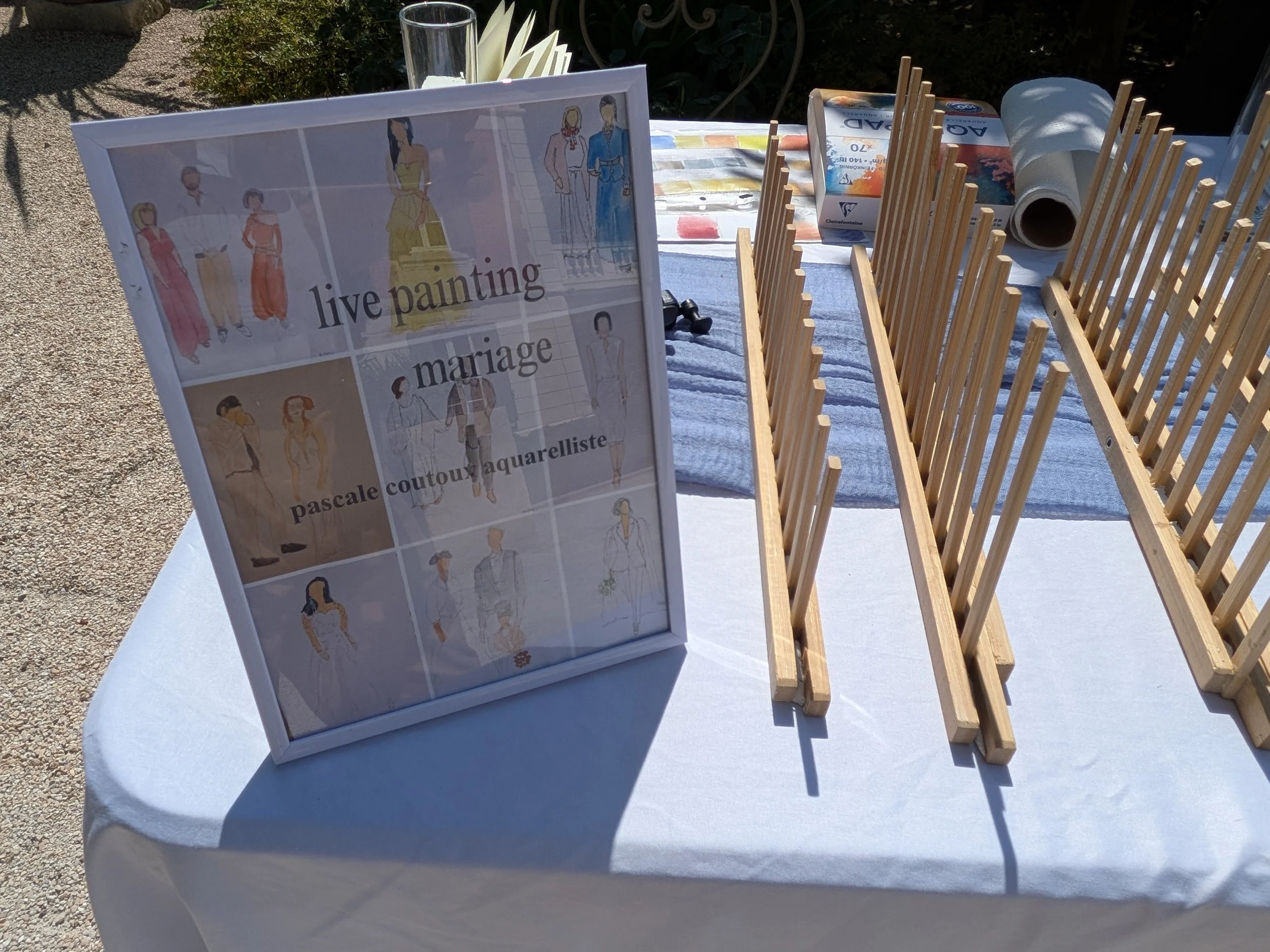 Installation de l'artiste de live painting mariage avec chevalets, aquarelles et exemples de portraits personnalisés.