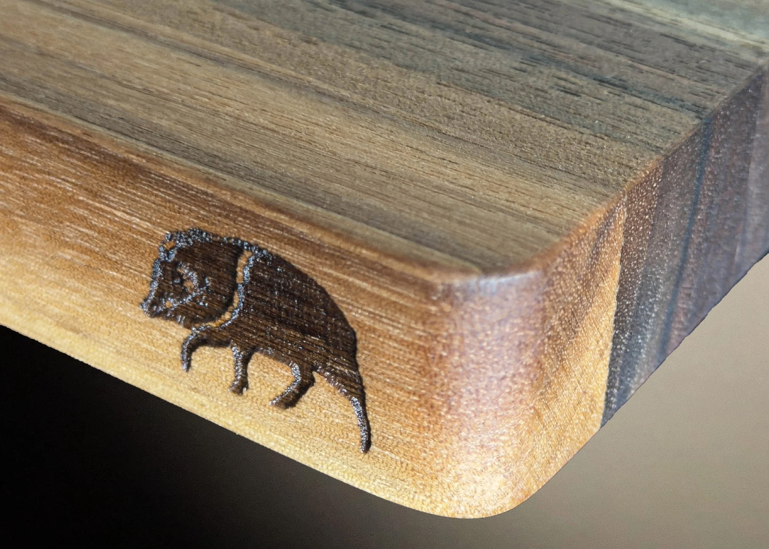 Close-up of a wooden cutting board with a javelina laser etched on the side.