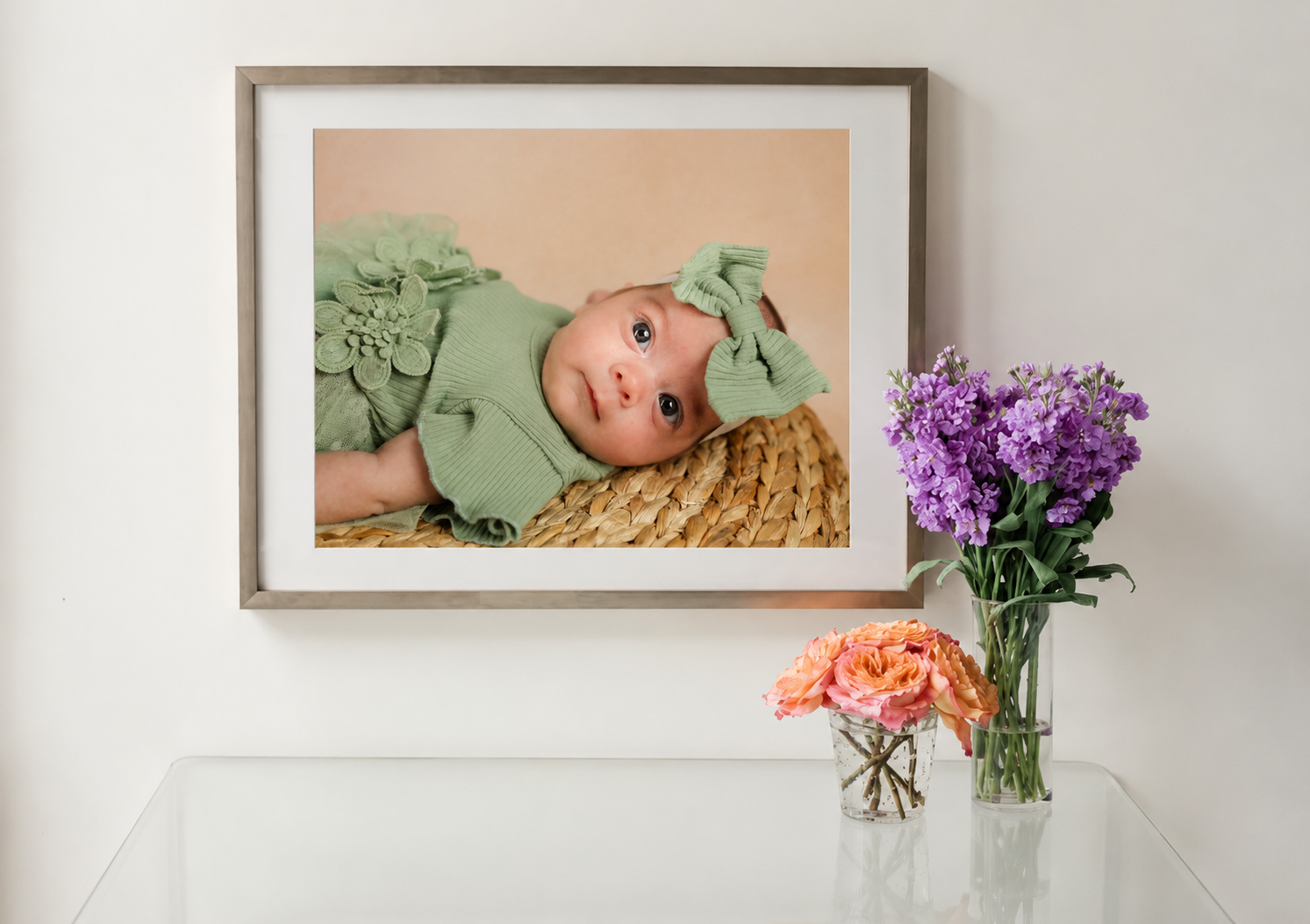 baby in green outfit laying down for school photo with flowers on shelf