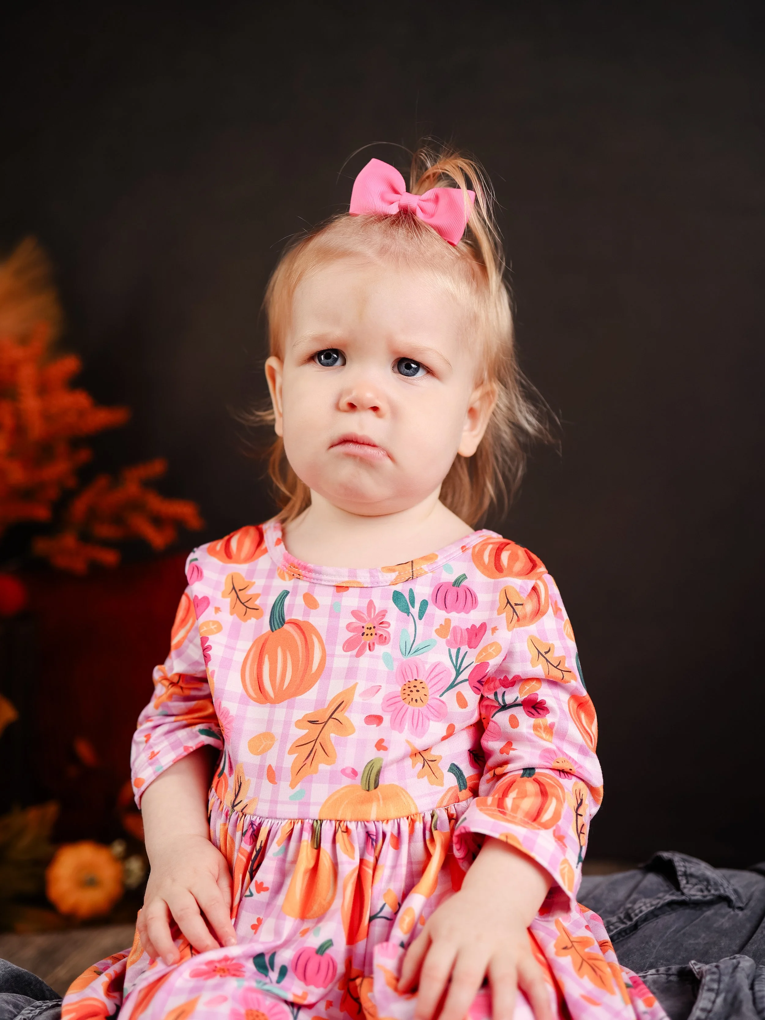 preschooler sitting for fall photos with pouty face