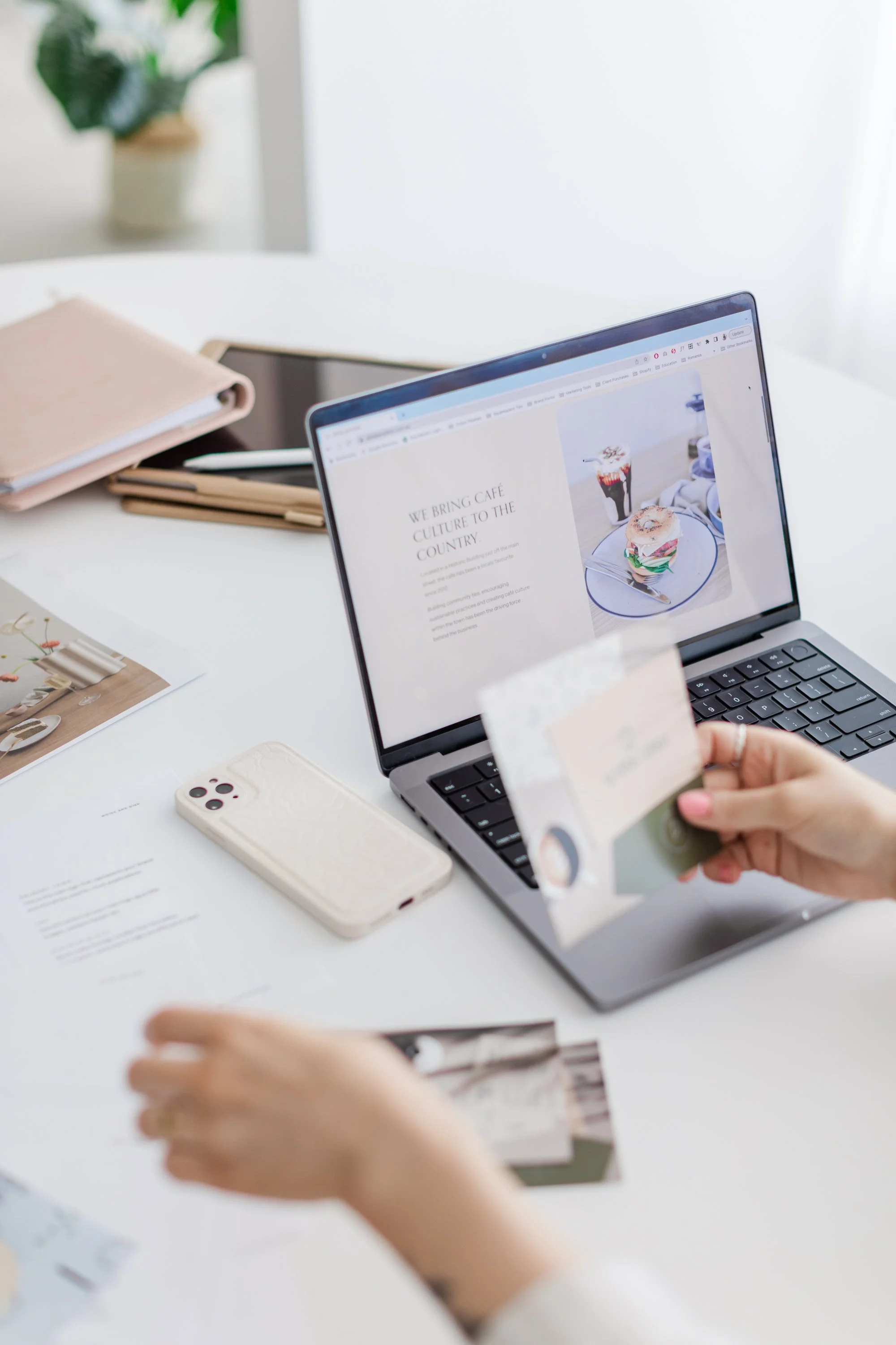Person using a laptop at a desk with papers and smartphone.