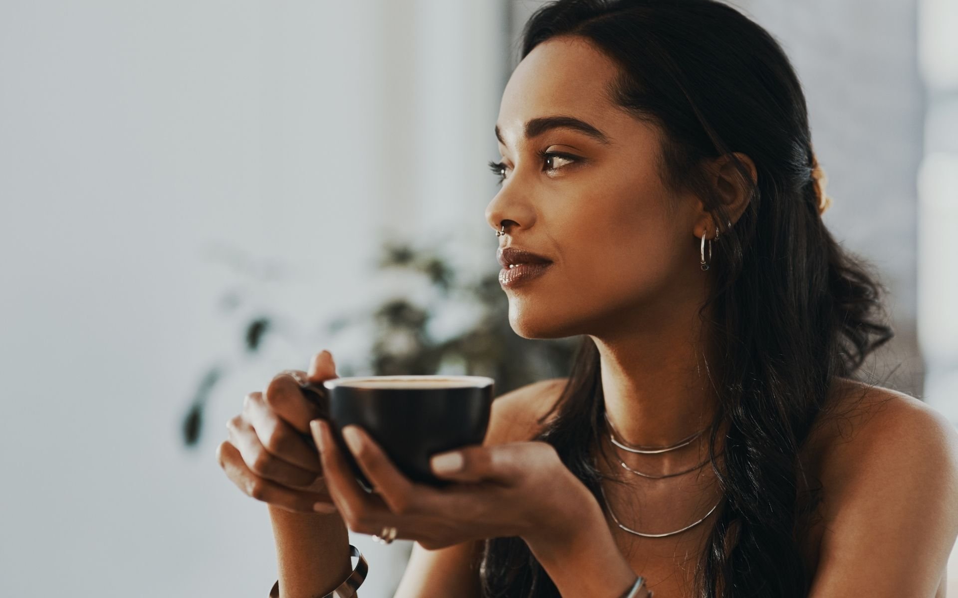 Black woman drinking tea in peaceful setting, practicing self-compassion and reflection