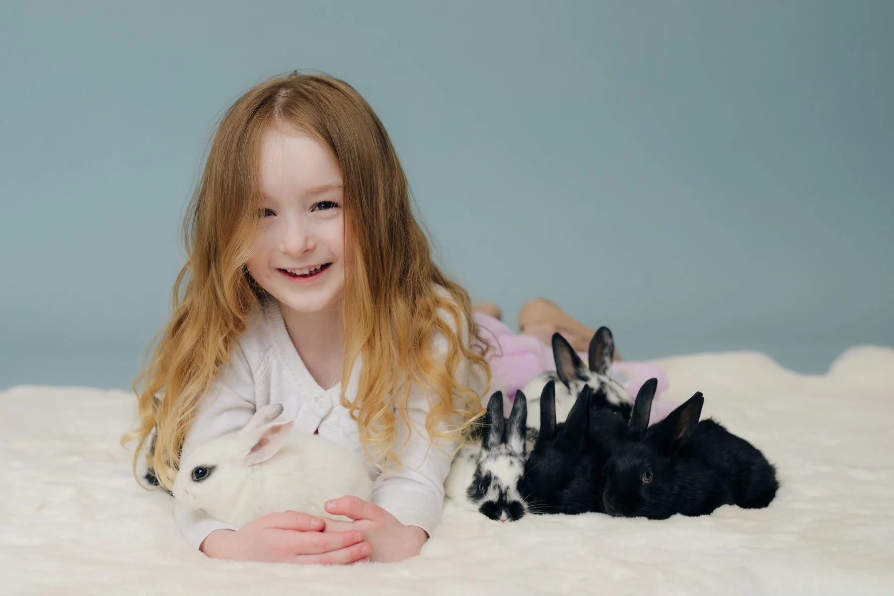 little girl laying with baby bunnies