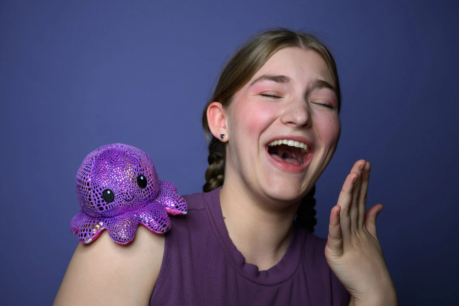 A plush octopus on her shoulder and she is laughing