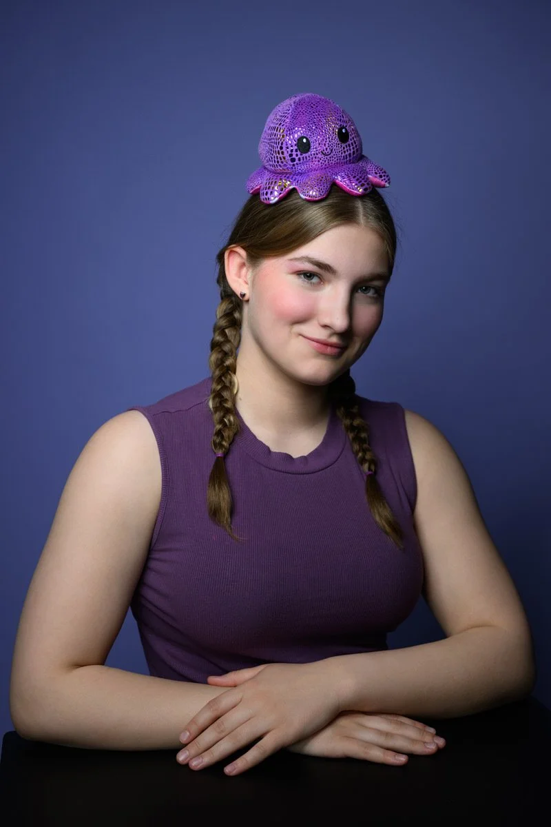Girl wearing a purple octopus on her head with a purple background