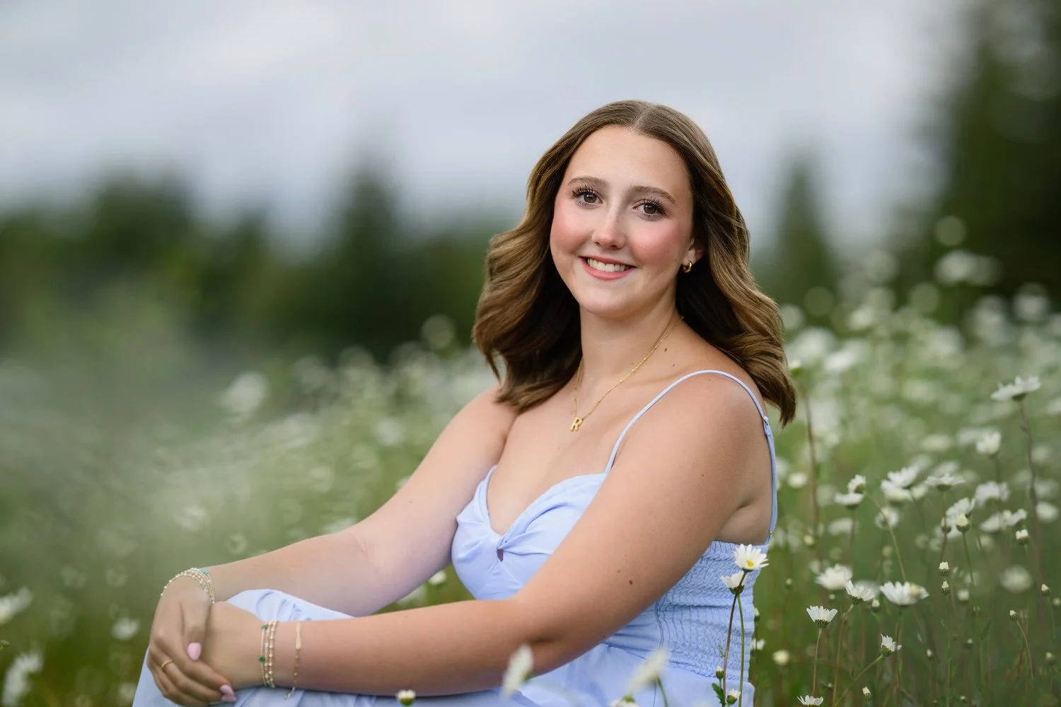 Senior girl sitting in a blue dress with wildflowers all around her