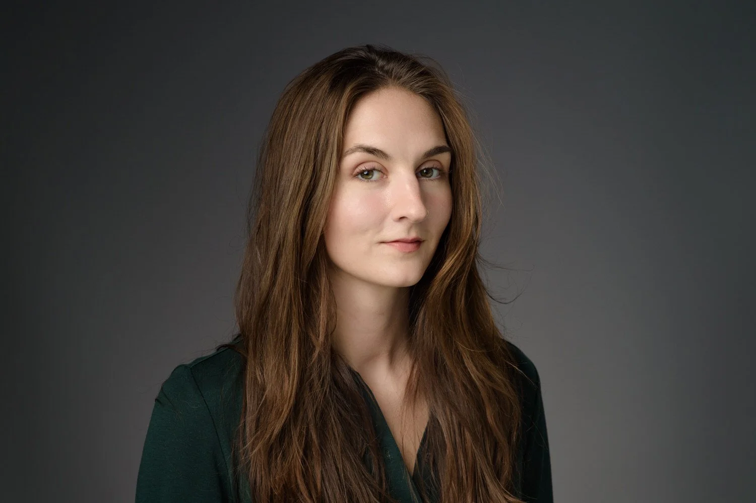 Headshot taken against a grey background of beautiful women with long brown hair. 