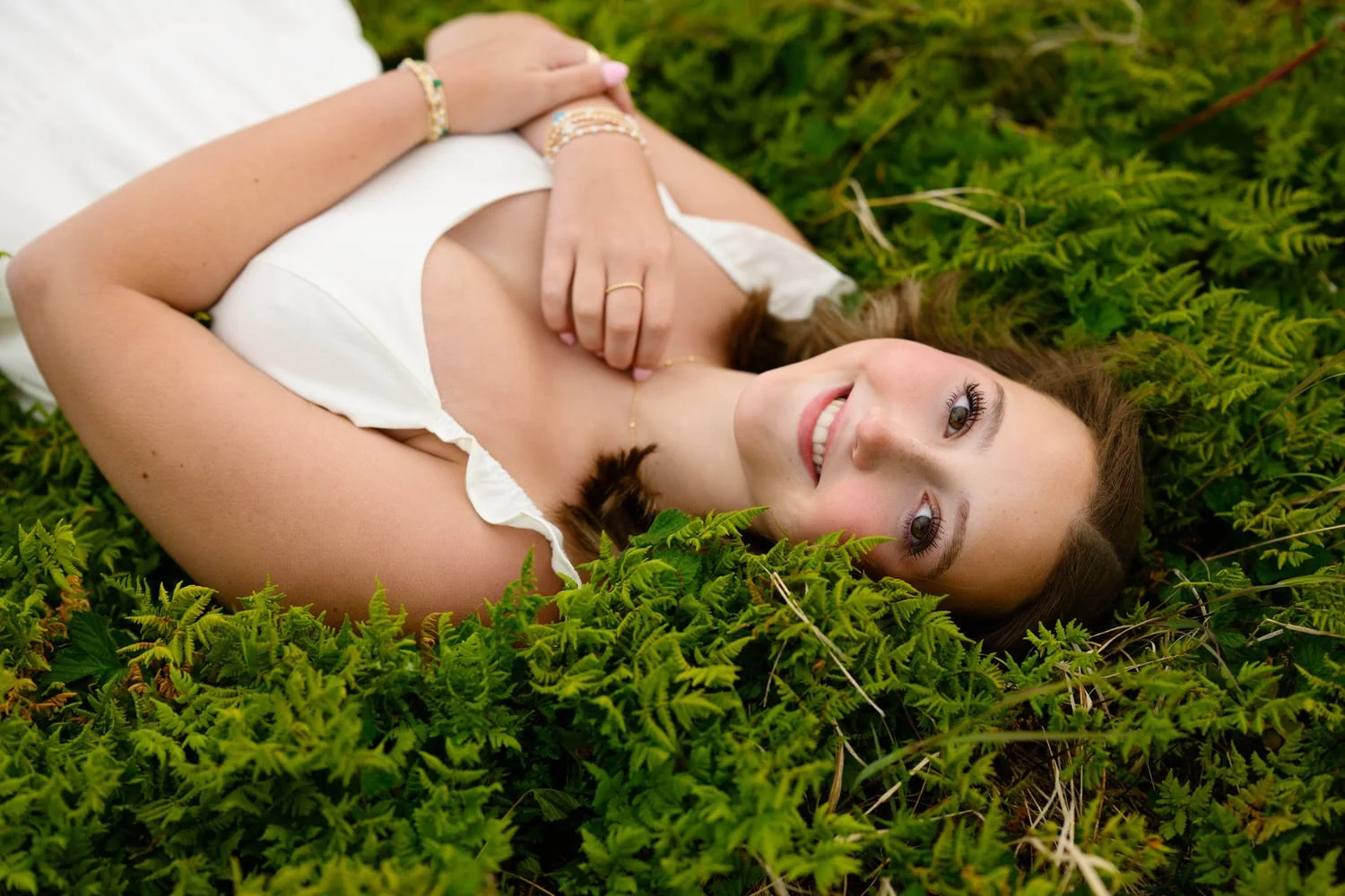 High school senior girl laying in green ferns in Alaska
