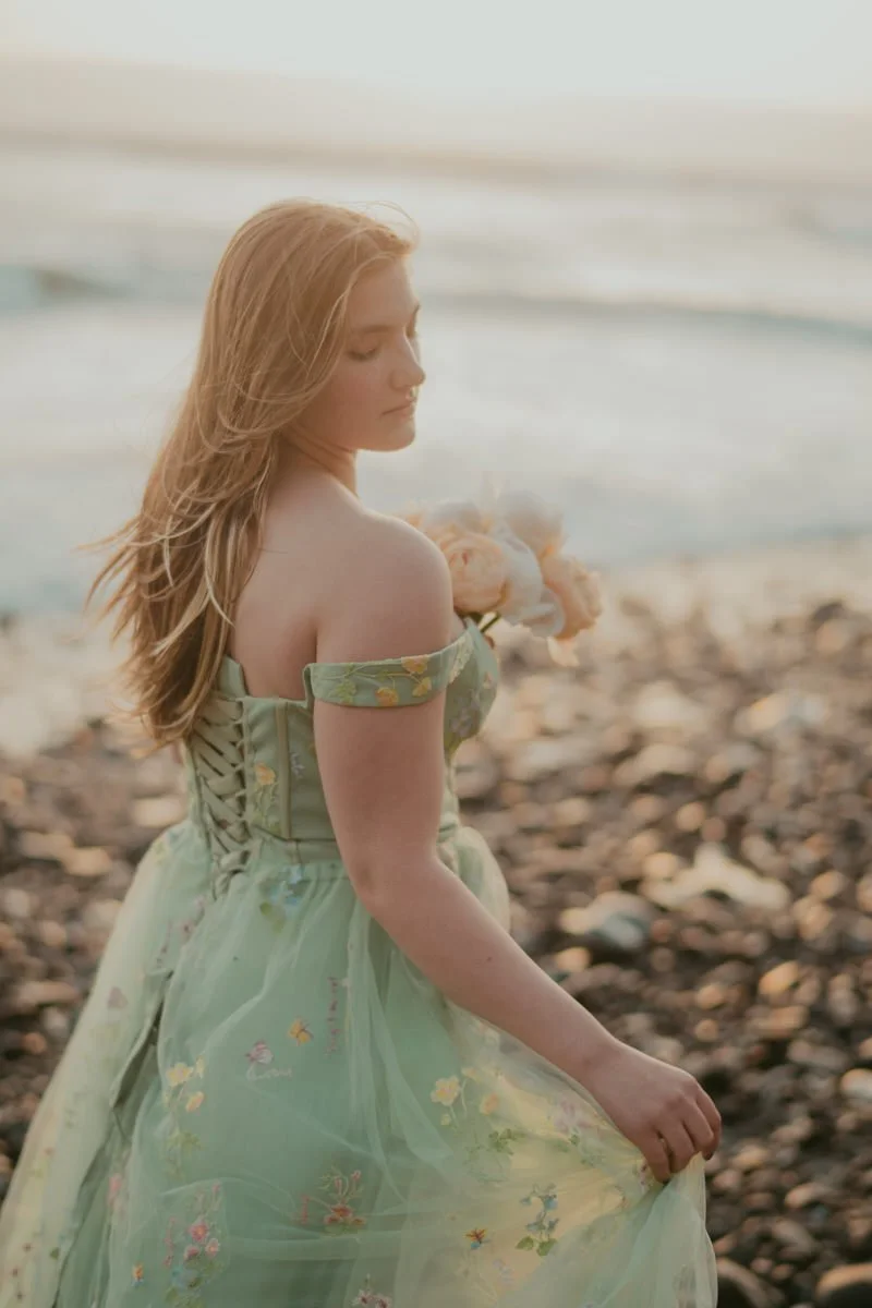Girl wearing a green dress walks along the beach