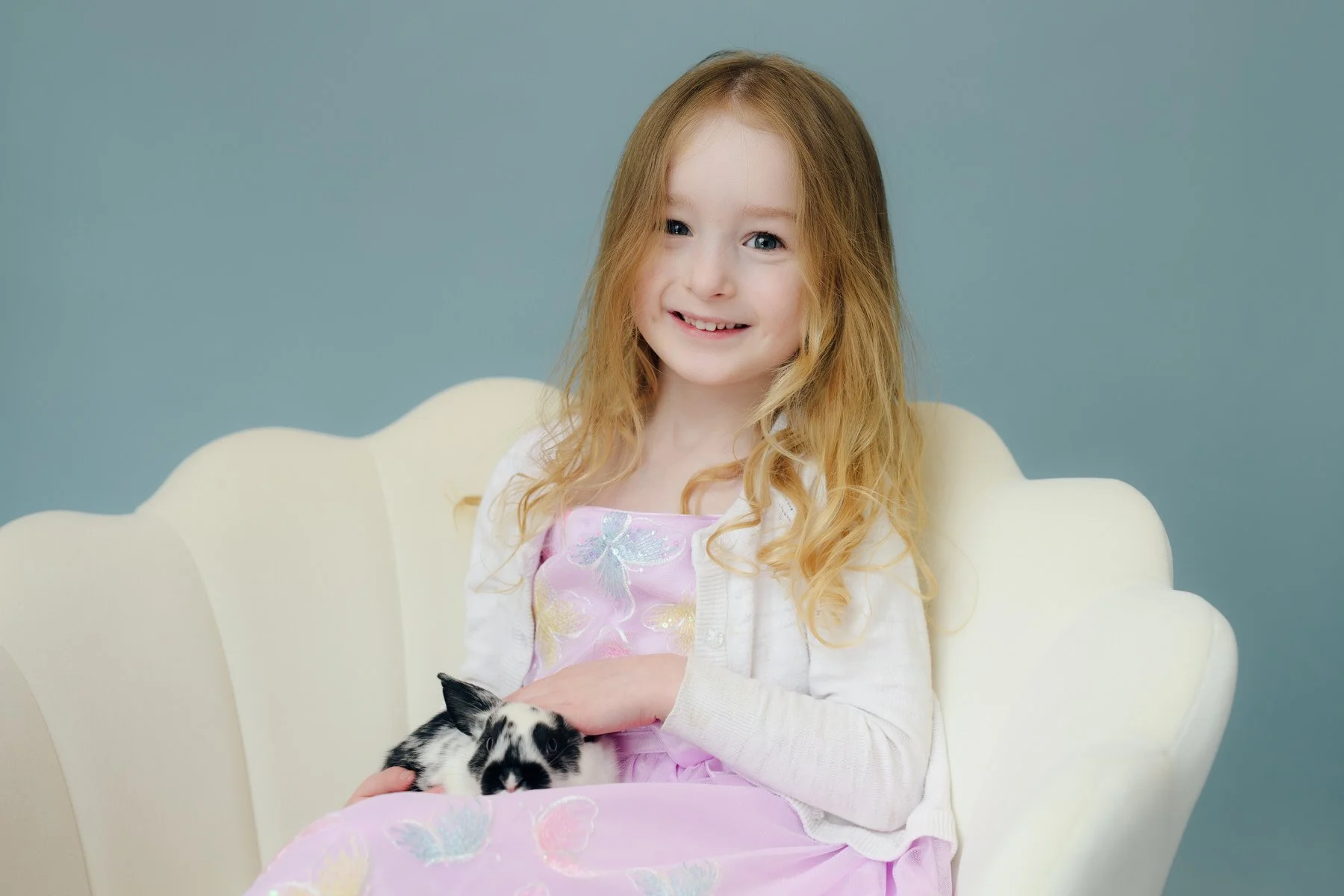 Little girl holding a baby bunny in portrait studio.
