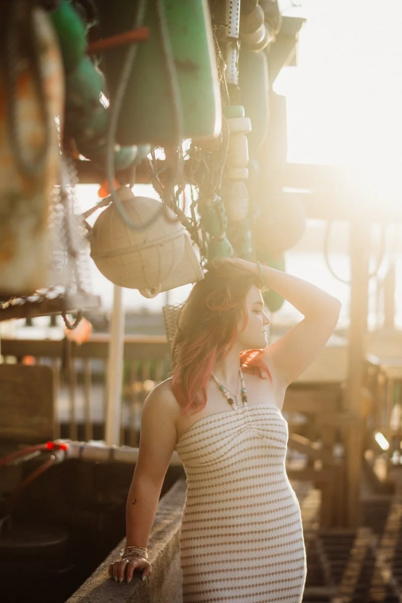 portrait of a girl standing on a marina with the sun coming in behind her for her senior portraits