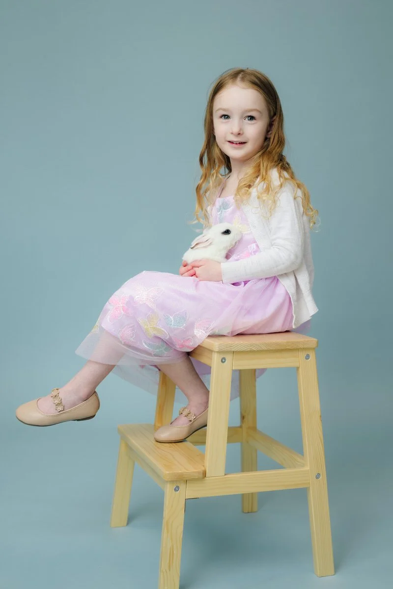 Girl sitting on a chair in studio with rabbit. 