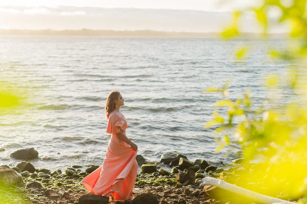 senior girl walking along the oregon coast for portraits wearing her pink prom dress