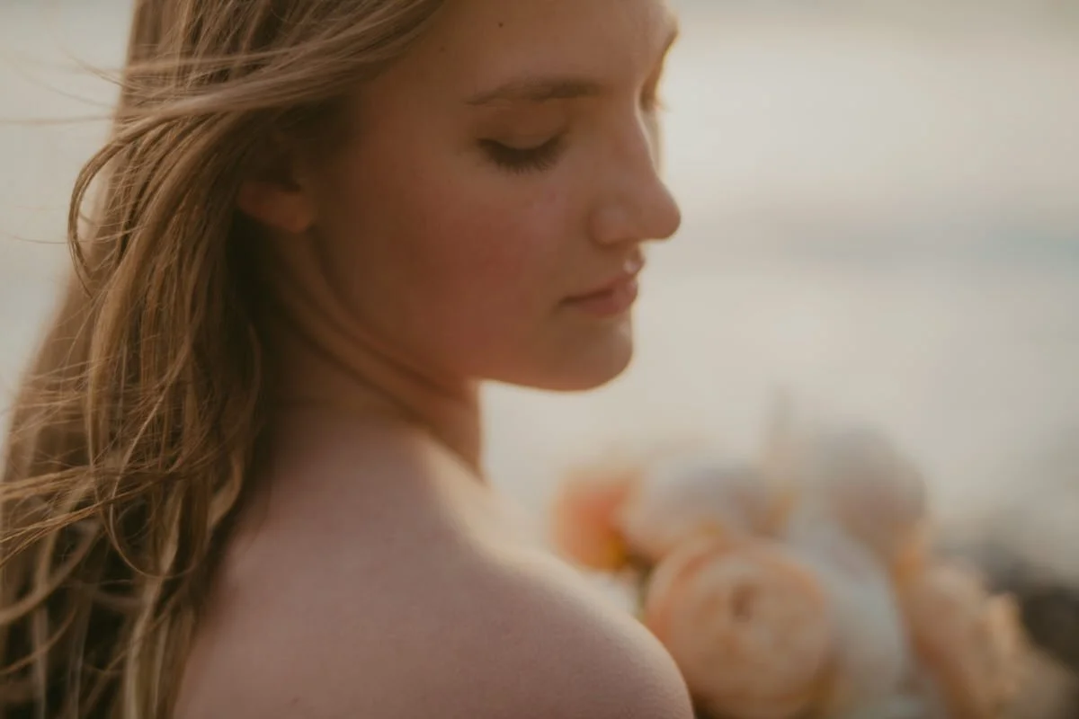 closeup portrait of a high school senior girl holding peonies and looking off to the side