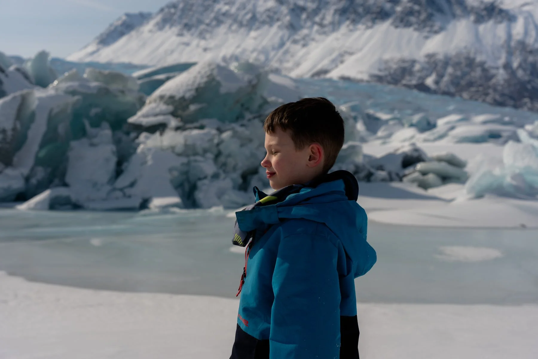 boy soaks up the sun with the knik glacier behind him