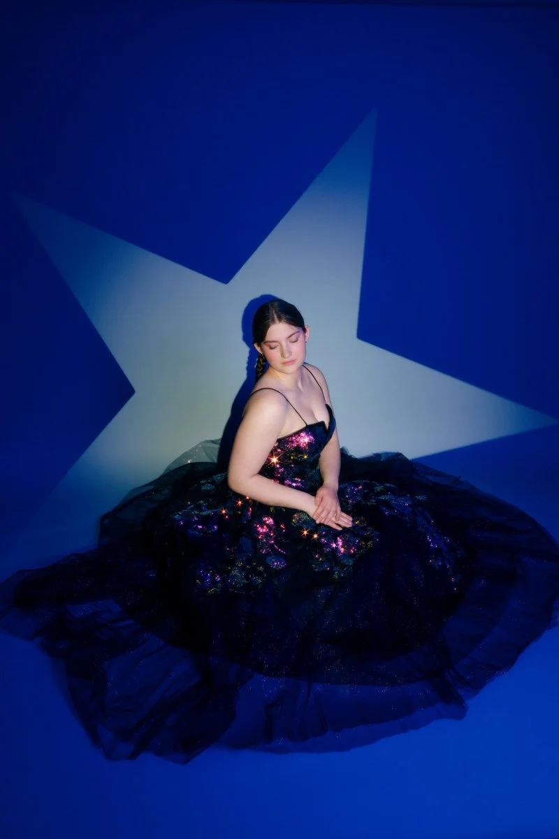 Girl with a star behind her and blue light sitting for a portrait