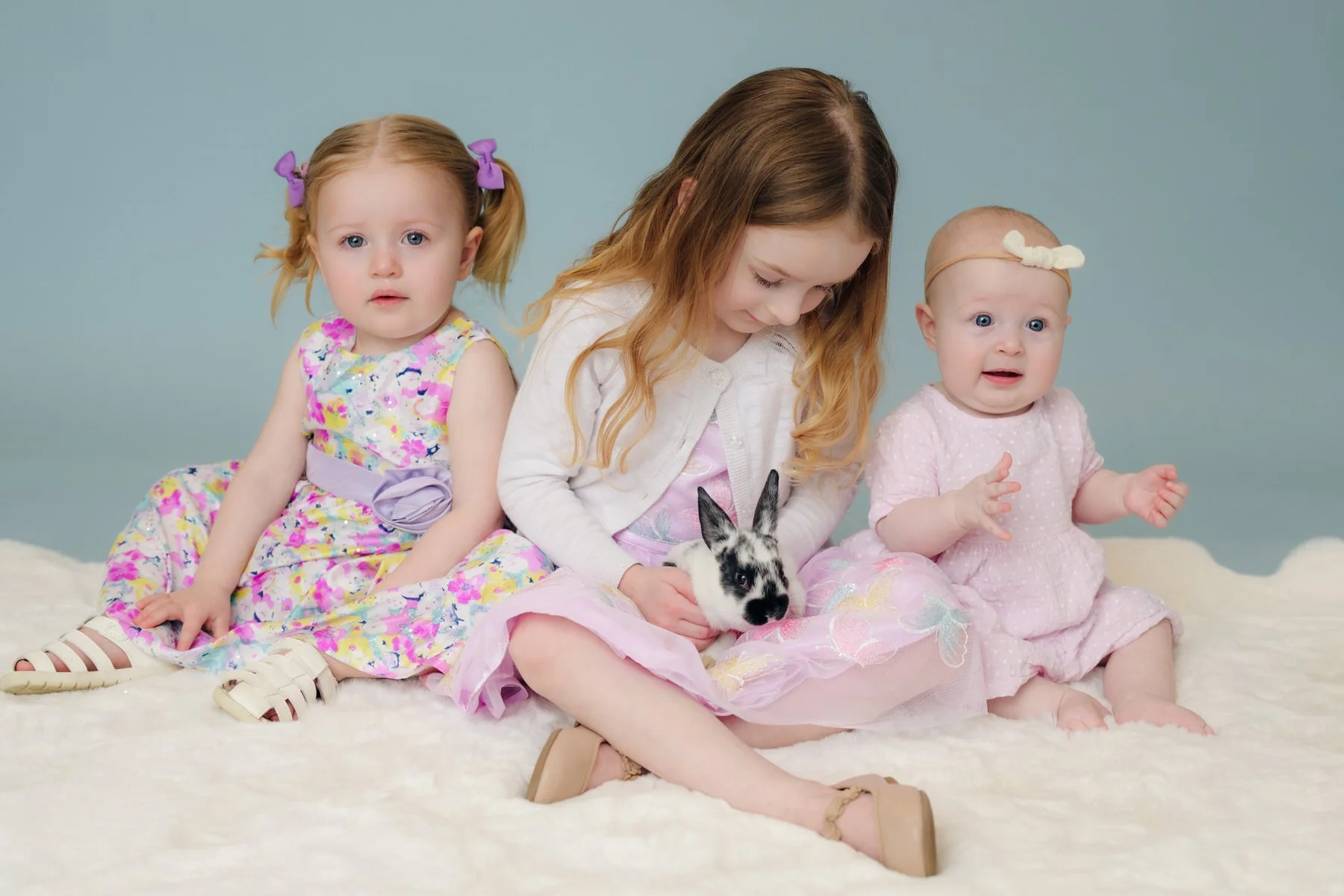 Sisters sitting with baby bunnies in easter clothing