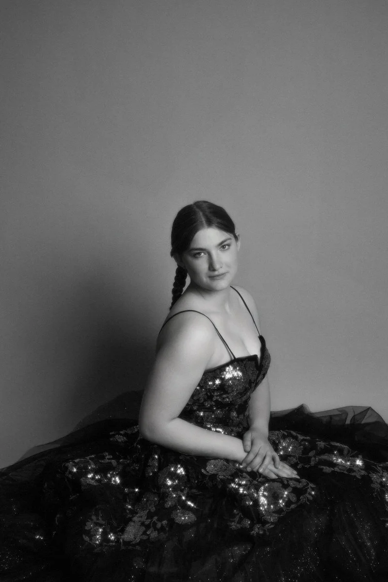 Black and white classic image of a girl sitting in her prom dress.