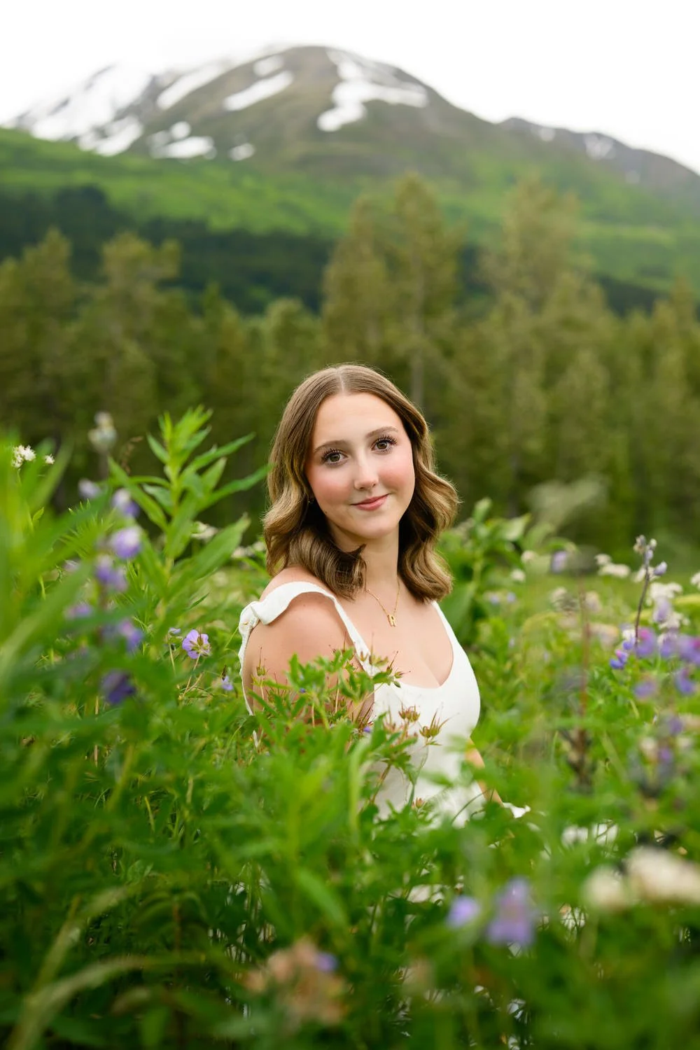 High school senior girl sitting in a green field with wildflowers
