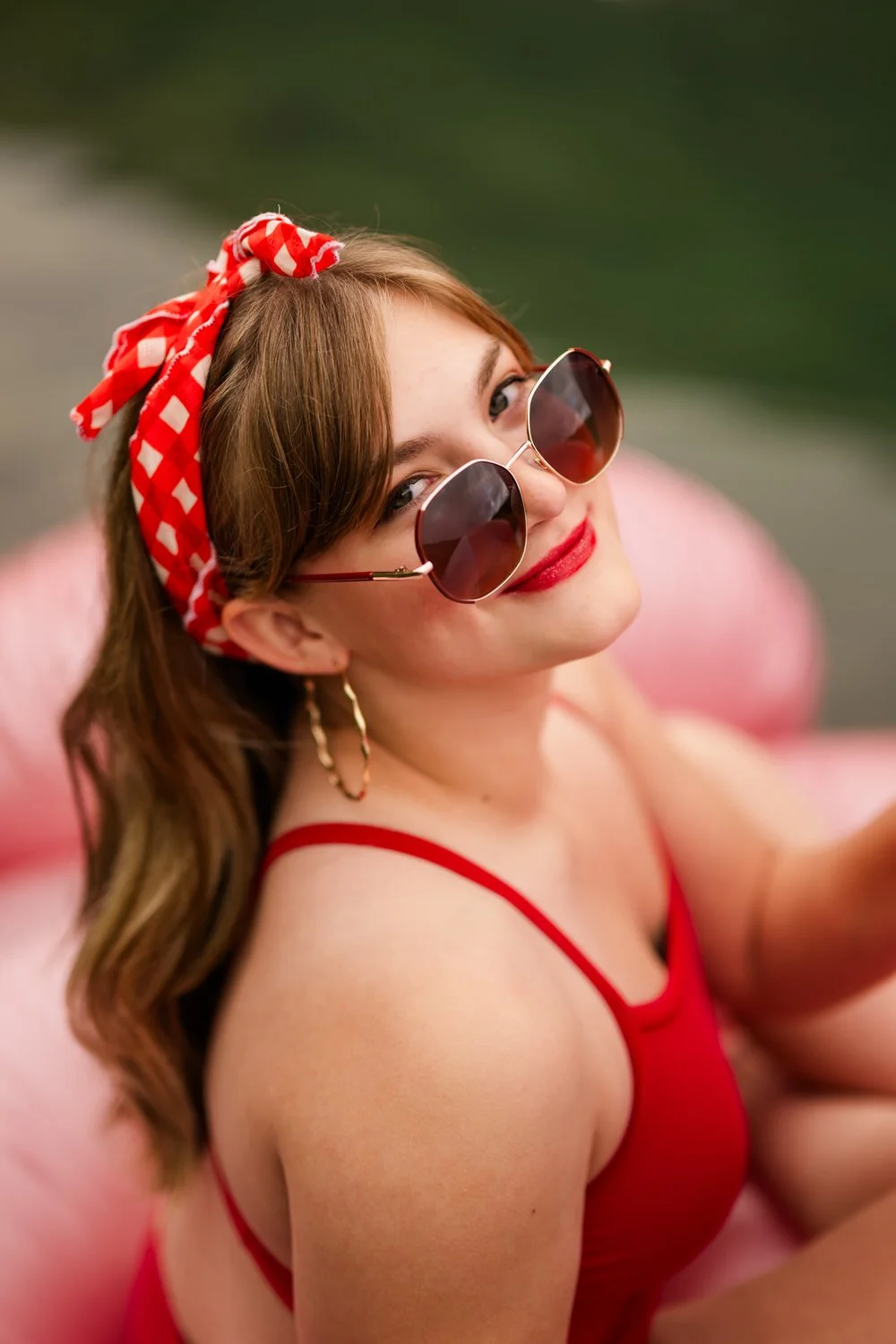 Cute portrait of a girl in a red swimming suit, wearing sunglasses, with a red bandana in her hair