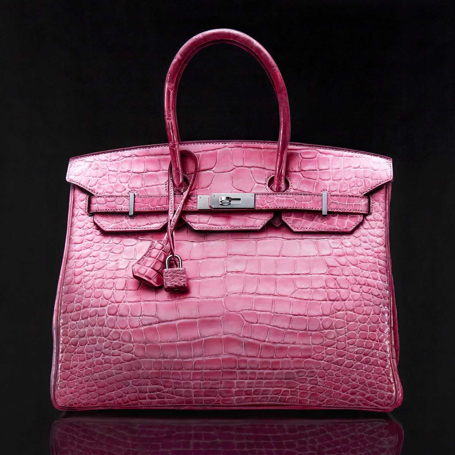 A pink crocodile skin luxury handbag with a lock and key, set against a black background.
