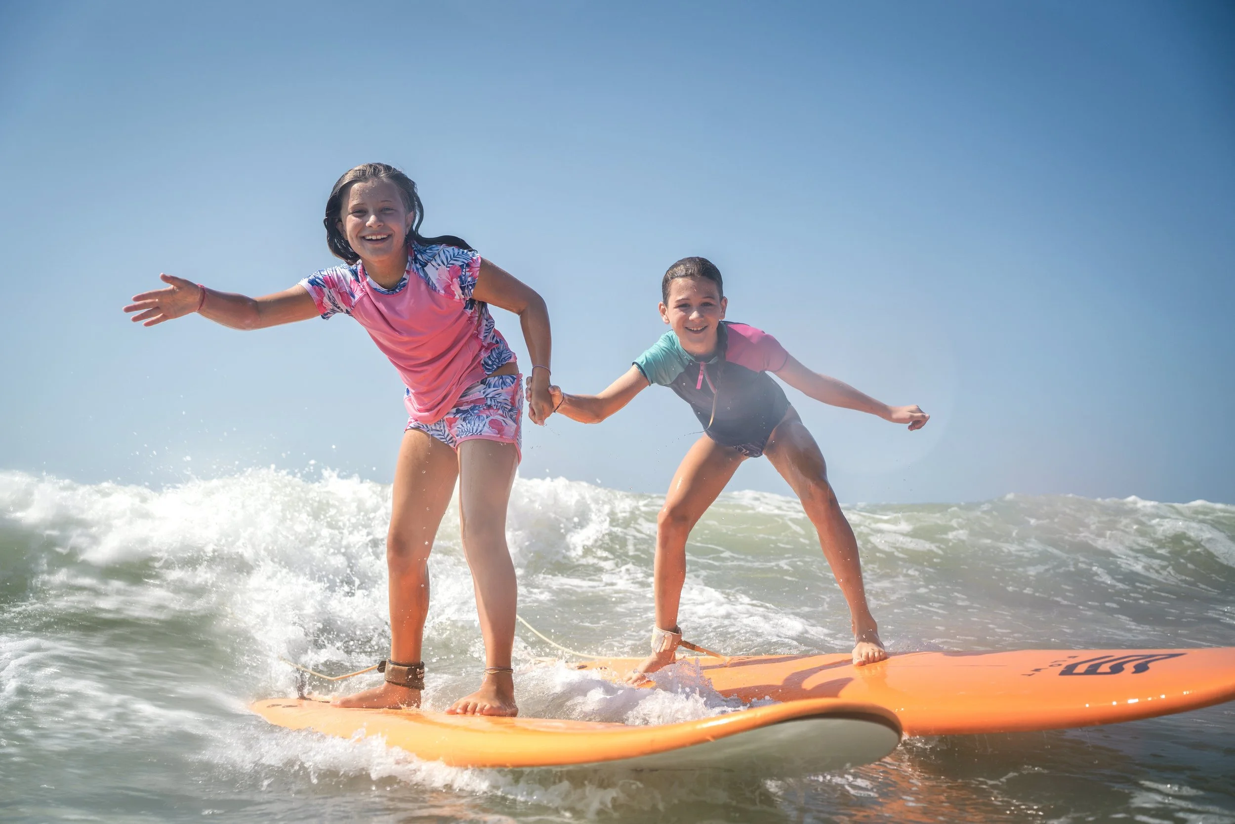 Sisters sharing a wave at Surf Camp