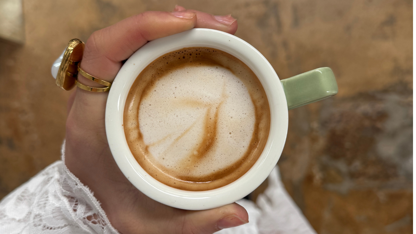Womans hand holding onto a warm hot cup of coffee.