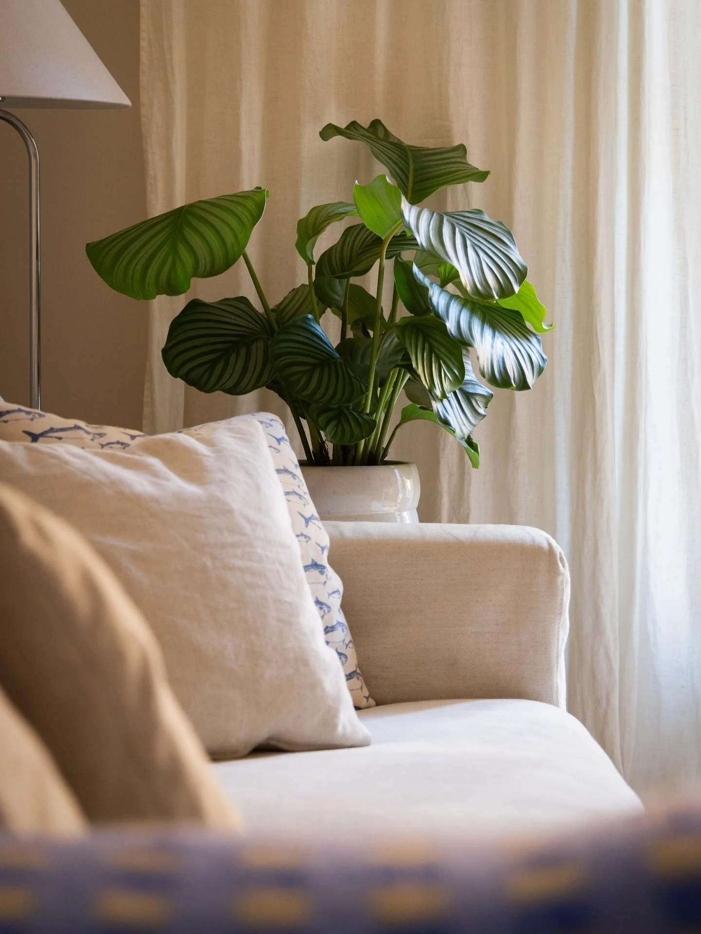 Det beiga vardagsrummet lyser i en varm ton. Det gula huset mittemot f&ouml;rst&auml;rker det varma.
F&aring;ngar en favoritvinkel fr&aring;n detta hem, rakt l&auml;ngsmed soffan, mjukt ljus mot gardinen och med sk&auml;rpa p&aring; en st&aring;tlig 