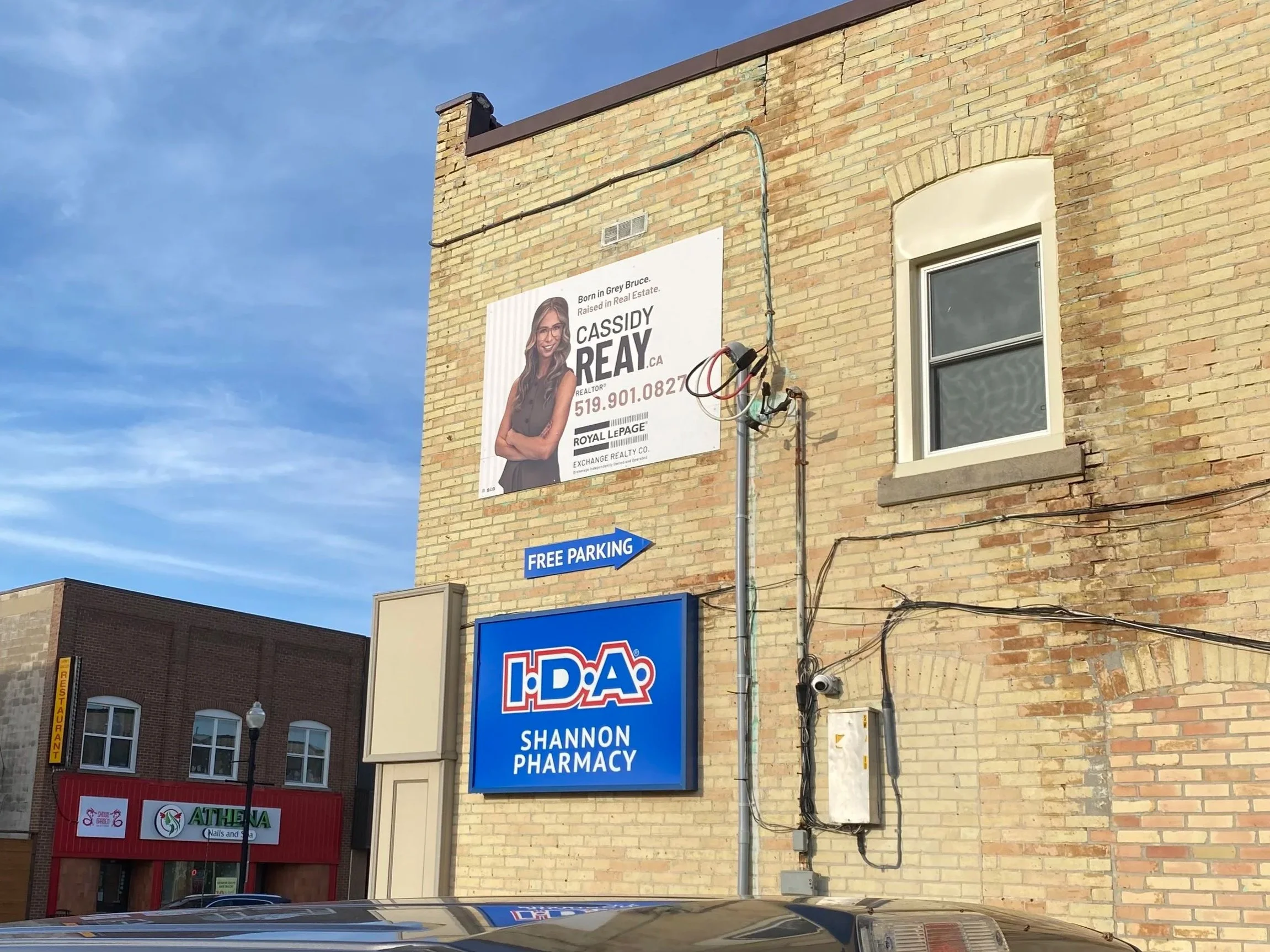 A brick building with billboard for Cassidy Reay - Signupsigns - Neustadt.