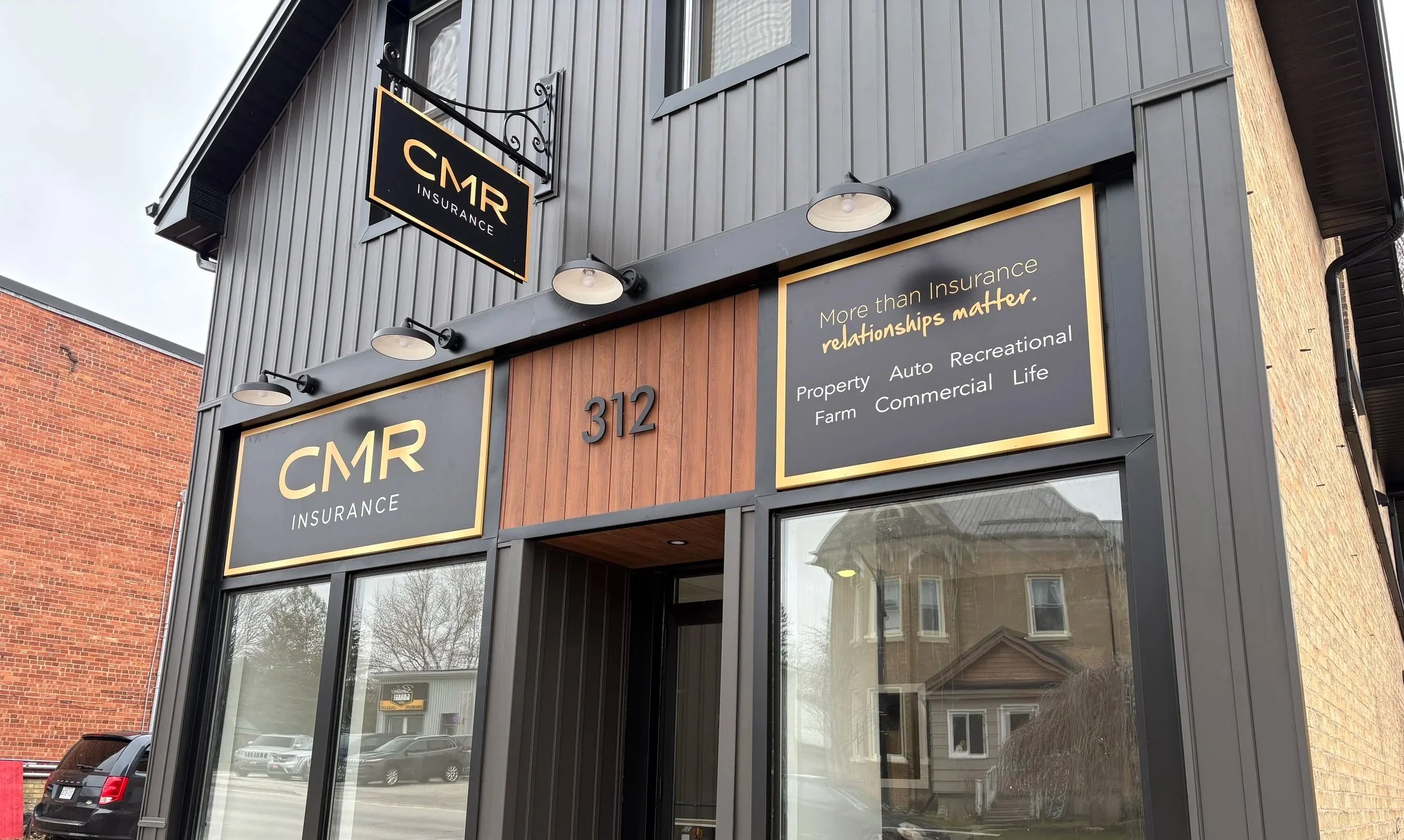 Exterior of a building with signage reading 'CMR Insurance' and a slogan 'More than Insurance, relationships matter.' The building has a modern facade with black and wood accents, large glass windows - Signupsigns - Neustadt.